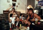 Joseph Rodriguez Peter drinks a beer with a friend as his children watch TV Spanish Harlem NY 1987