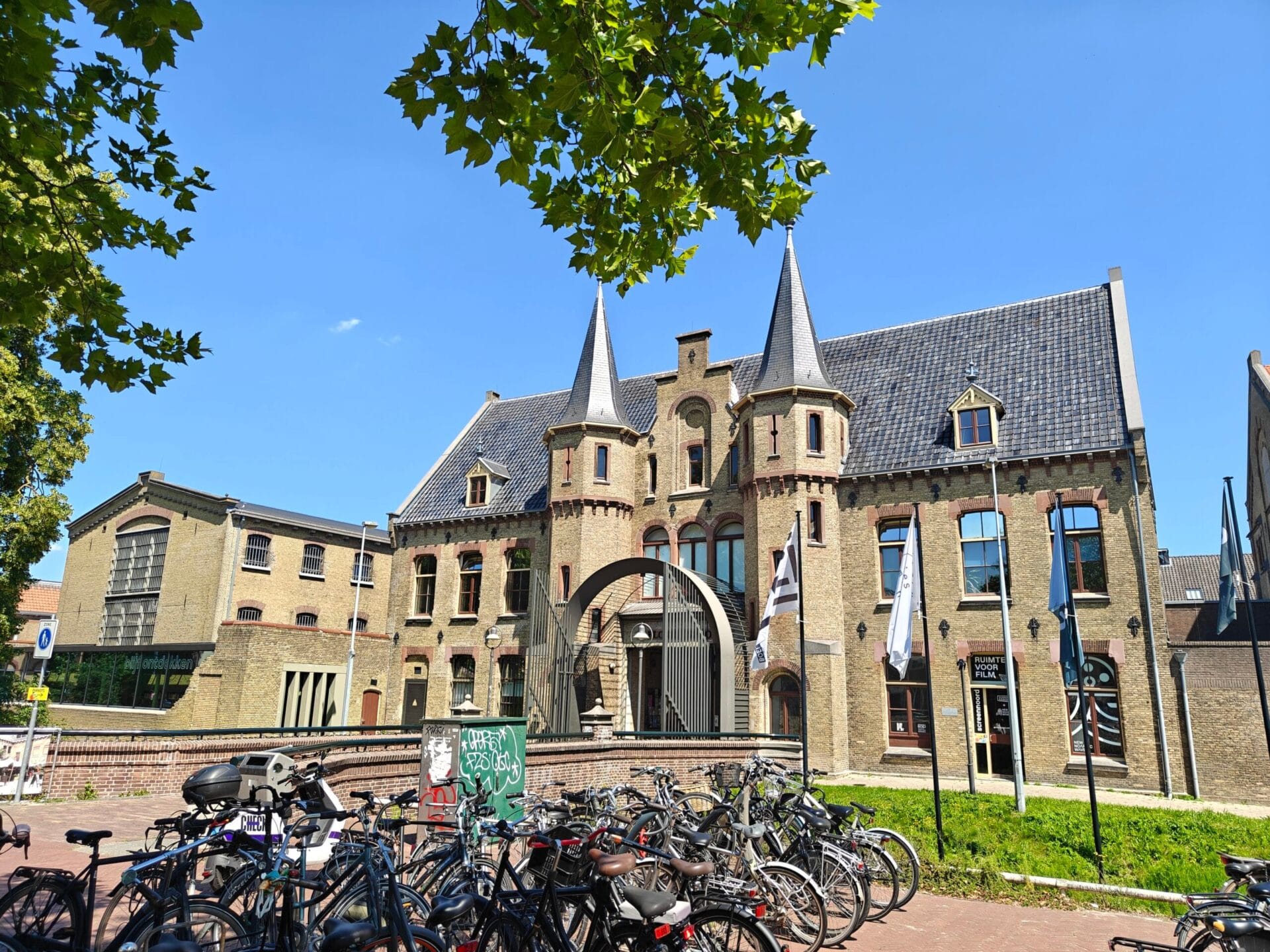 Buitenopname van een historisch bakstenen gebouw met torentjes onder een blauwe lucht, gefotografeerd met de Nord 5CE
