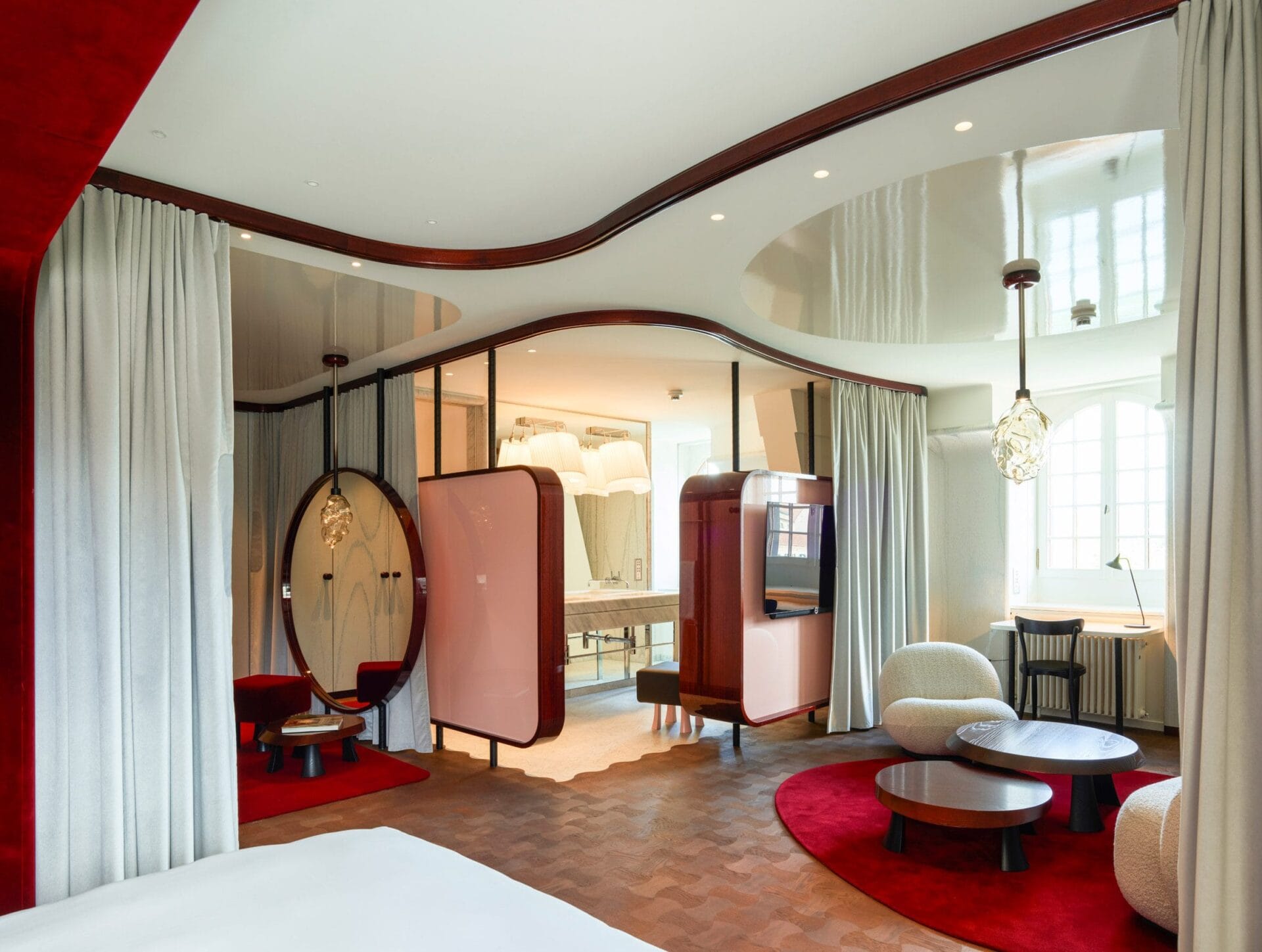 Modern interieur van een suite in Hotel Les Trois Rois met rode kleden, mahoniehouten accenten en glanzend witte plafonds