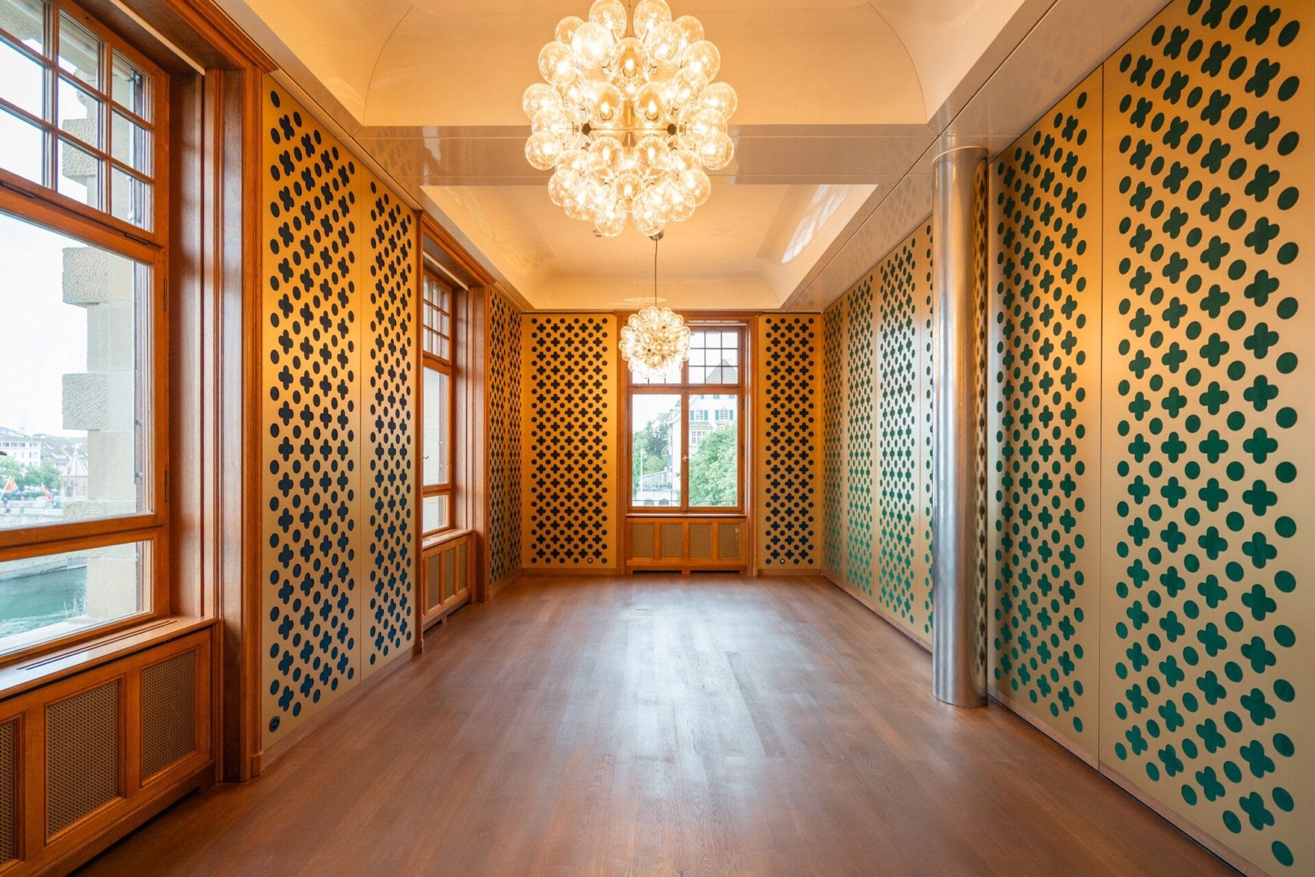 Modern interieur van een suite in Hotel Les Trois Rois met houten vloeren, grote kroonluchters en wanden met patronen