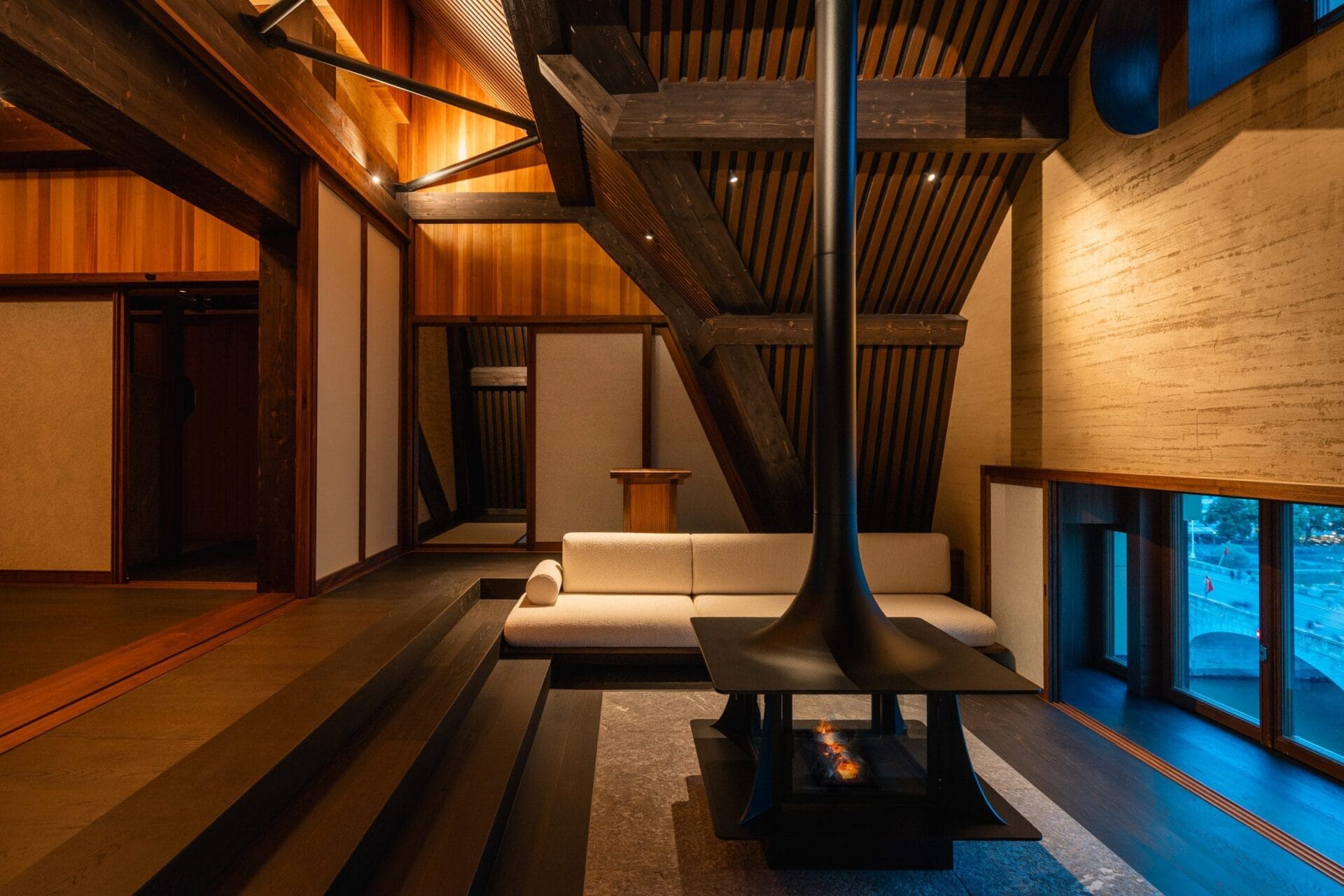 Minimalistisch interieur van de spa met houten balken, tatami-matten en een centrale haard met uitzicht op de stad