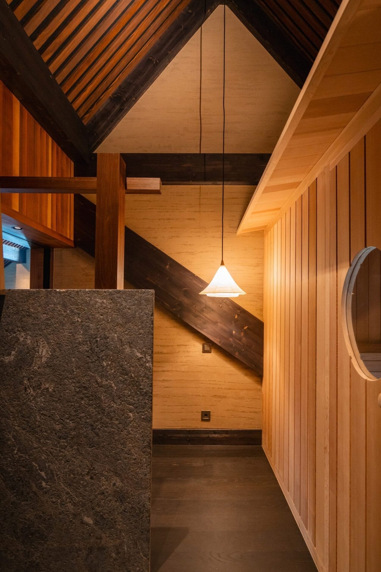 Minimalistisch interieur van de spa met houten wanden, donkere balken en een hanglamp in Japanse onsen-stijl