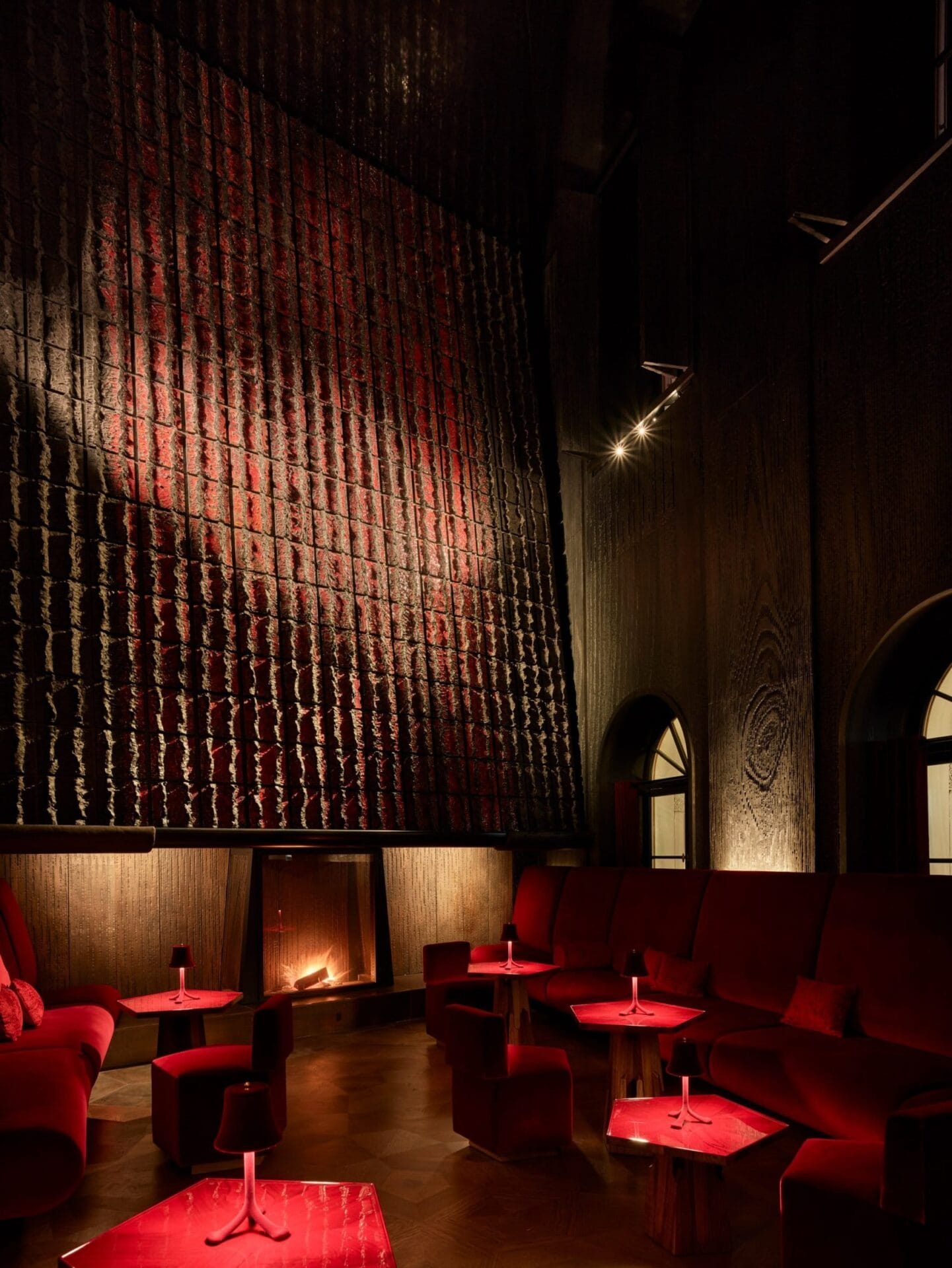 Lounge voor rokers in Hotel Les Trois Rois met rode banken, kleine tafels en een grote open haard