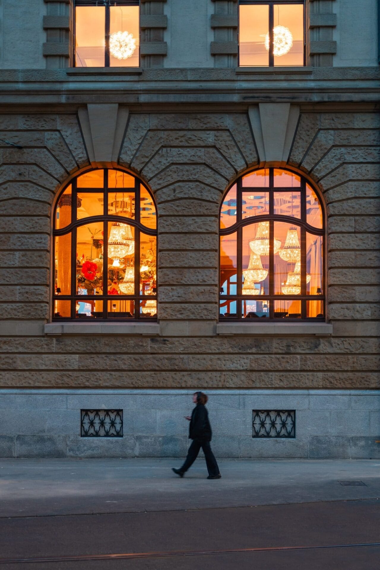 Buitenaanzicht van Hotel Les Trois Rois met verlichte kroonluchters zichtbaar door grote boogvensters