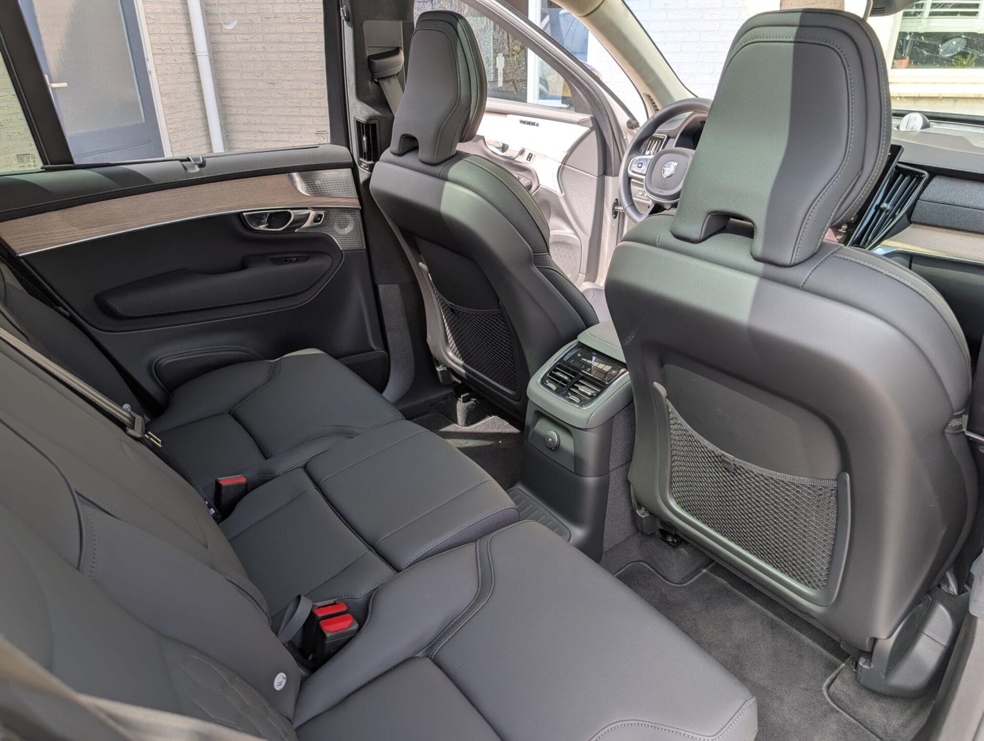 Het ruime interieur van de Volvo XC90 met lederen achterbank en houten afwerking in de deurpanelen