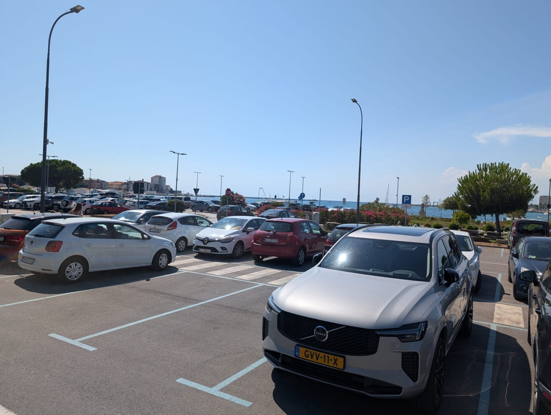 Een zilveren Volvo XC90 geparkeerd op een zonnige parkeerplaats aan de kust in Kroatië