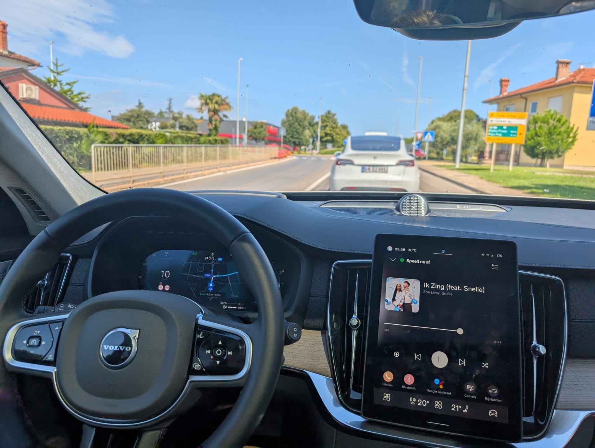 Zicht vanuit de cockpit van de Volvo XC90 met het digitale dashboard en de centrale tablet die muziek afspeelt