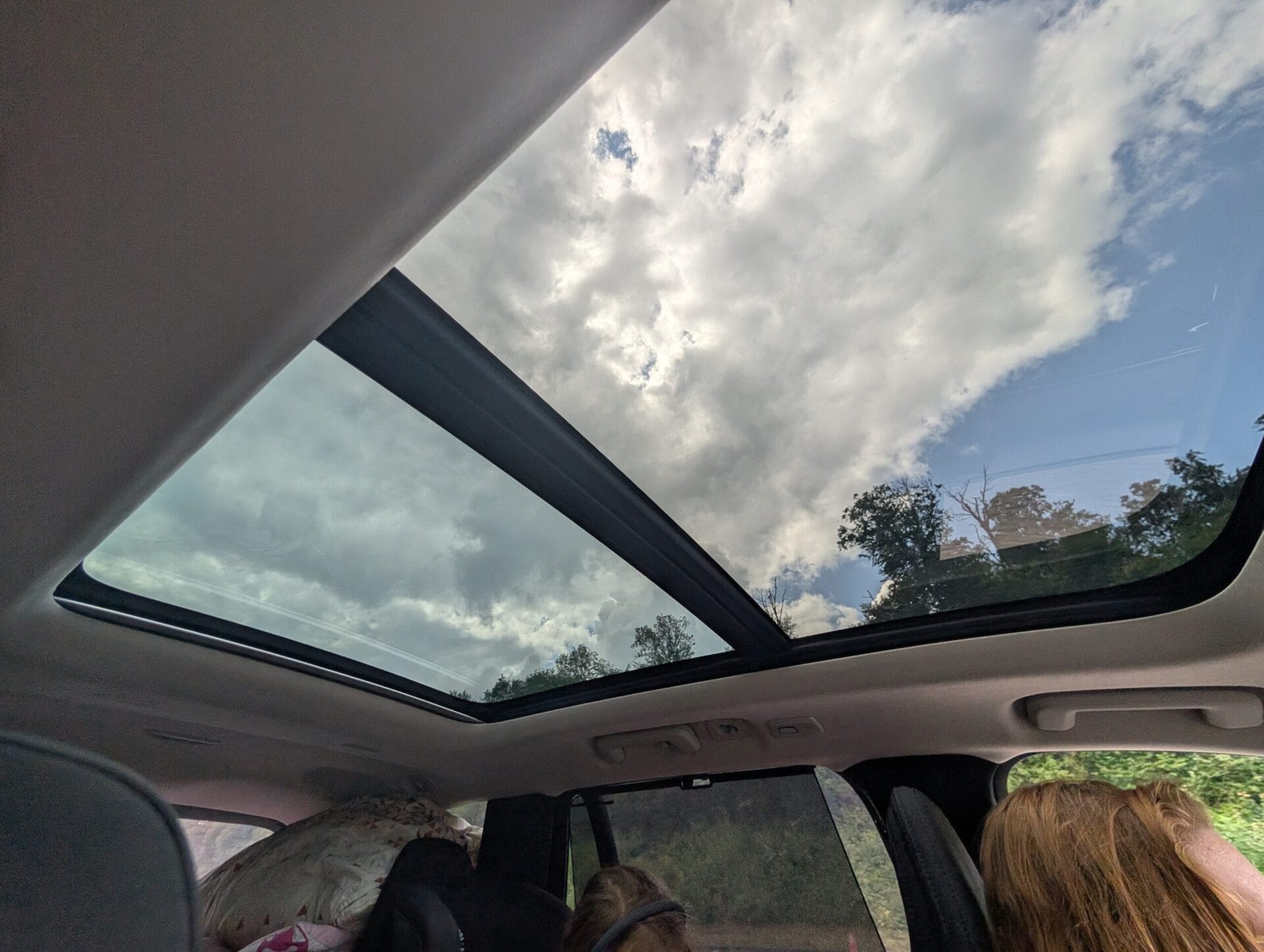 Zicht op de bewolkte lucht door het grote glazen panoramadak van de Volvo XC90