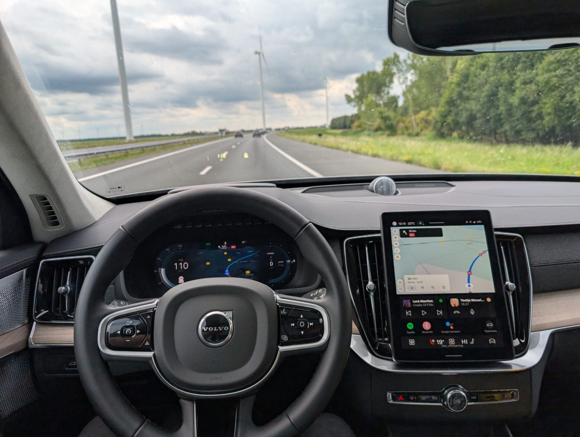 Het interieur van een Volvo XC90 tijdens het rijden op de snelweg, met focus op het digitale dashboard en infotainmentscherm