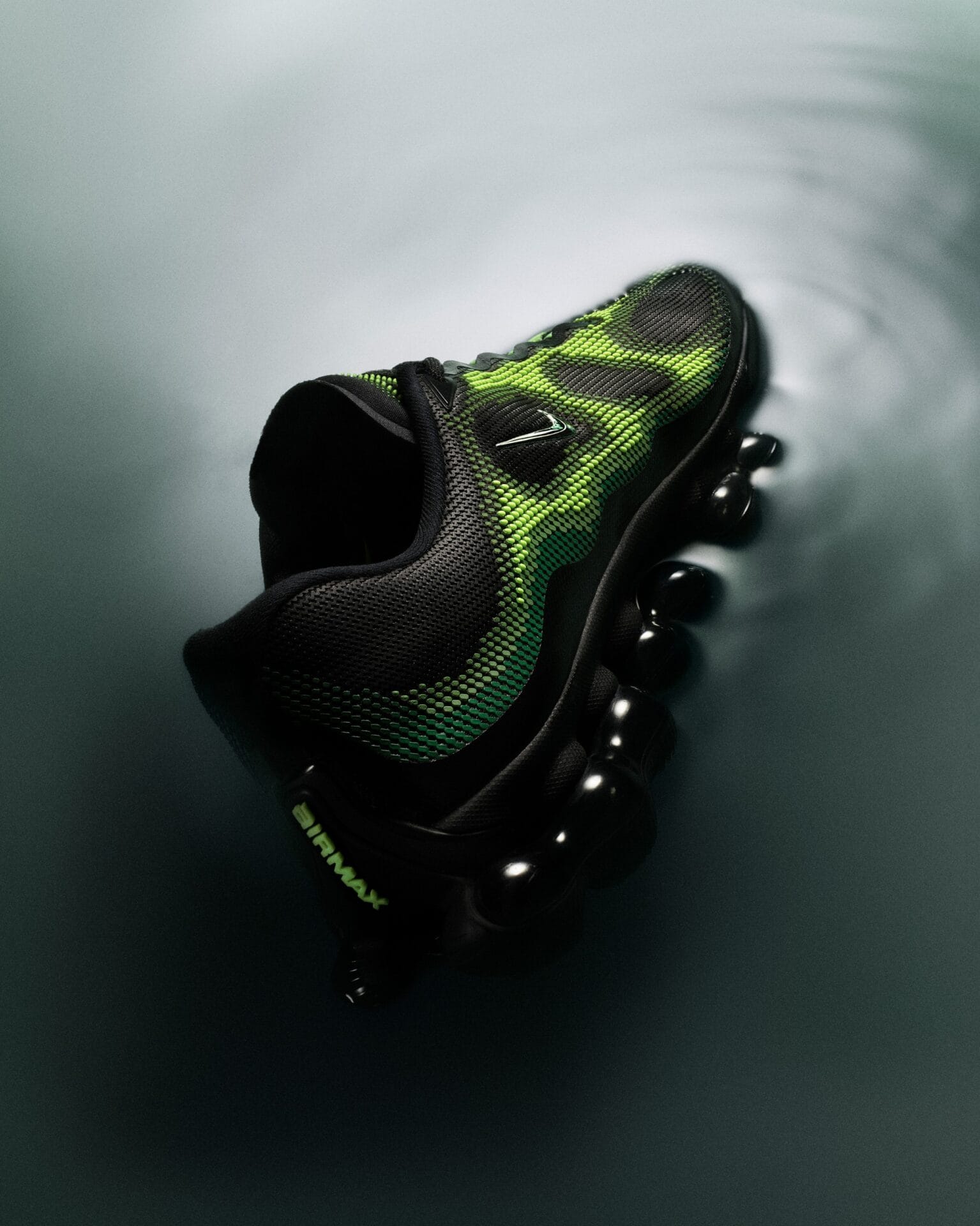 Nike Air Liquid Max sneaker met gifgroene nanoprint en een zwarte zool van bolvormige Air-units op een wateroppervlak