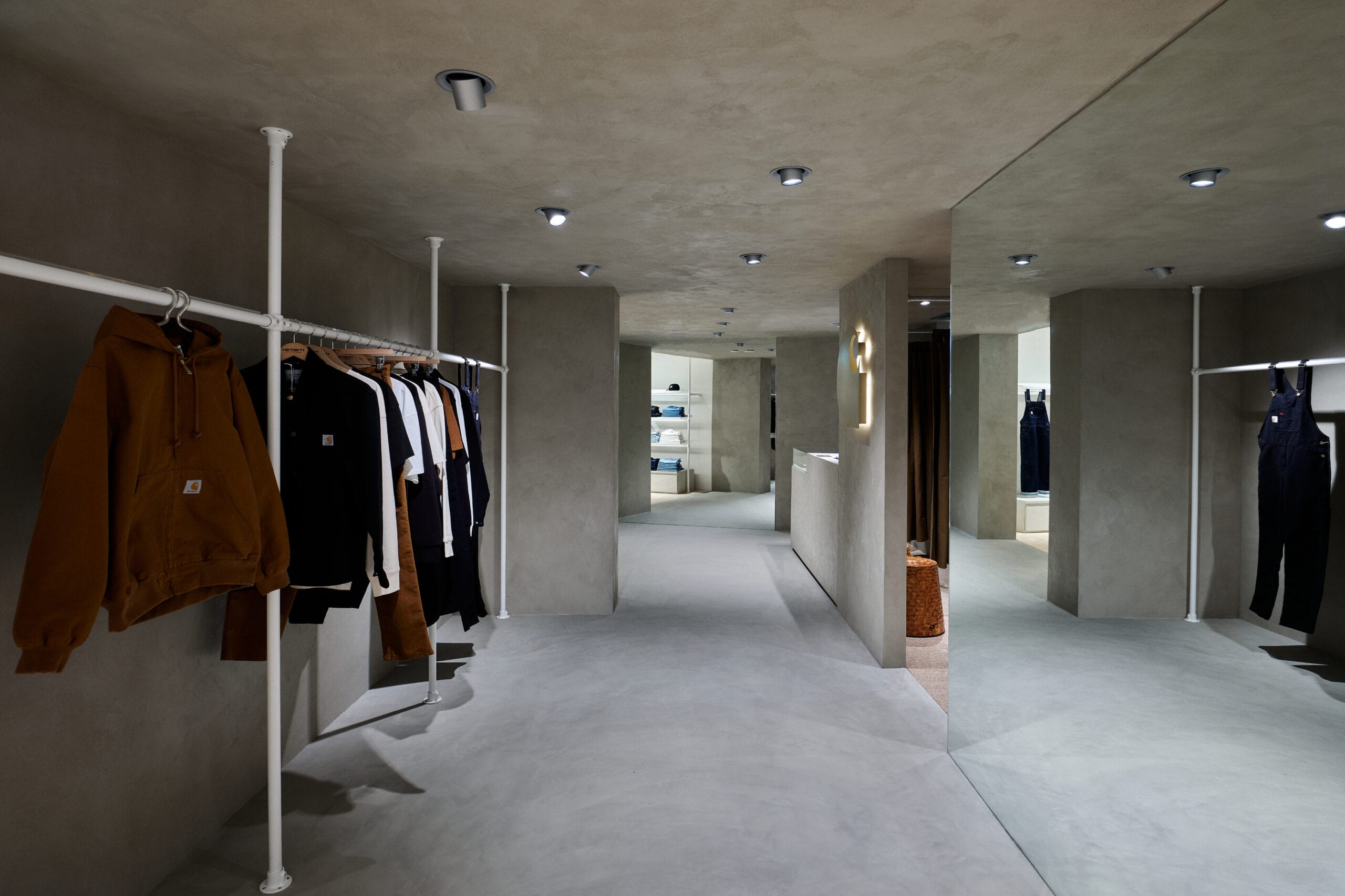 Interieur van een moderne kledingwinkel met betonnen muren, minimalistische kledingrekken en industriële verlichting