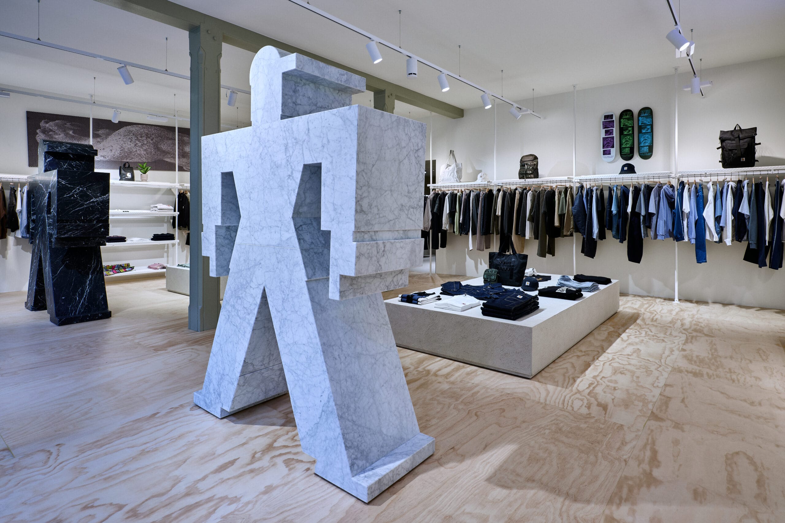 Interieur van een kledingwinkel met grote abstracte marmeren beelden en kledingrekken aan de wanden