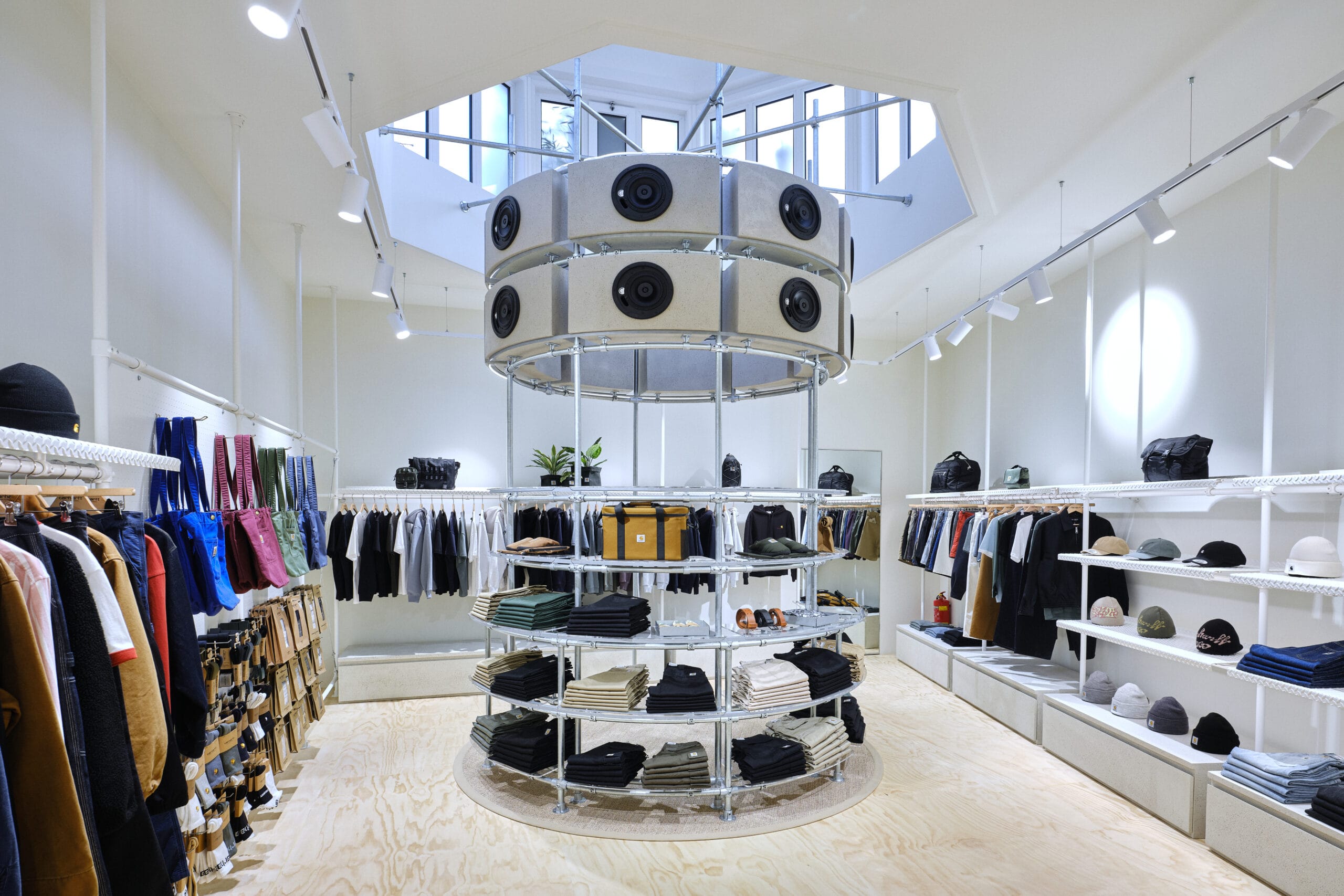 Interieur van een moderne kledingwinkel met een centrale ronde stelling en een opvallende luidsprekerinstallatie