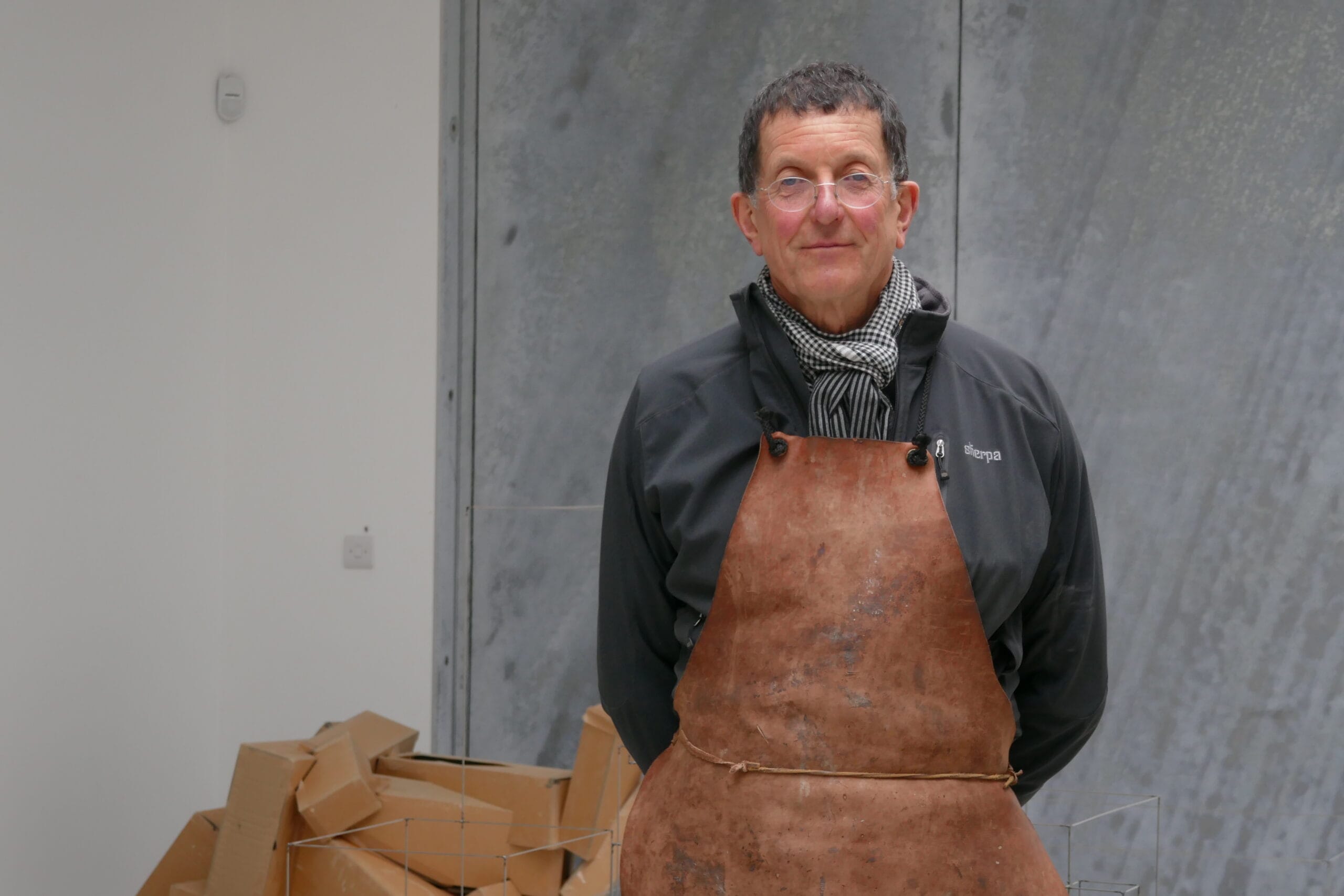 Portret van kunstenaar Antony Gormley in zijn atelier, dragend een leren schort en een sjaal