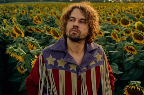 muzikant Kevin Morby staat in een veld vol zonnebloemen