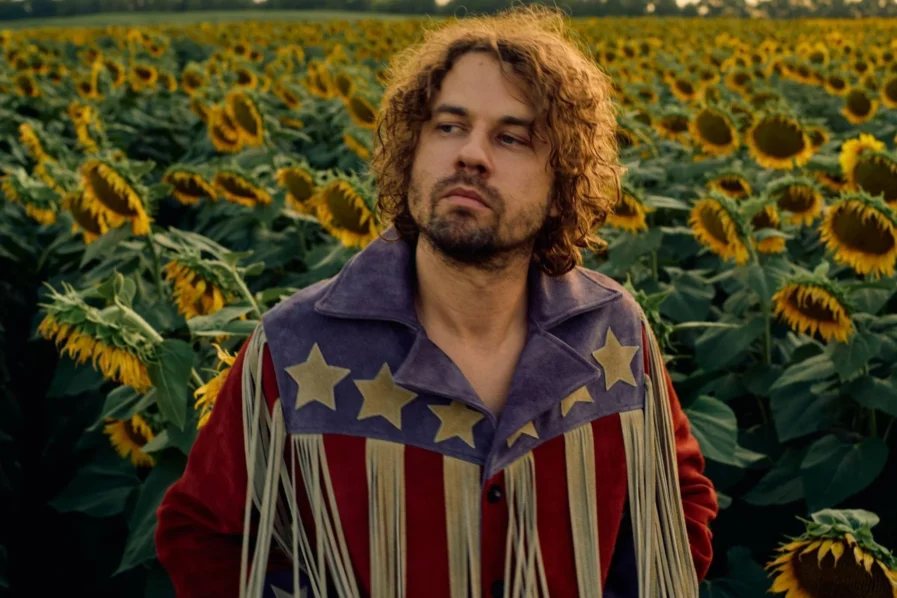 muzikant Kevin Morby staat in een veld vol zonnebloemen
