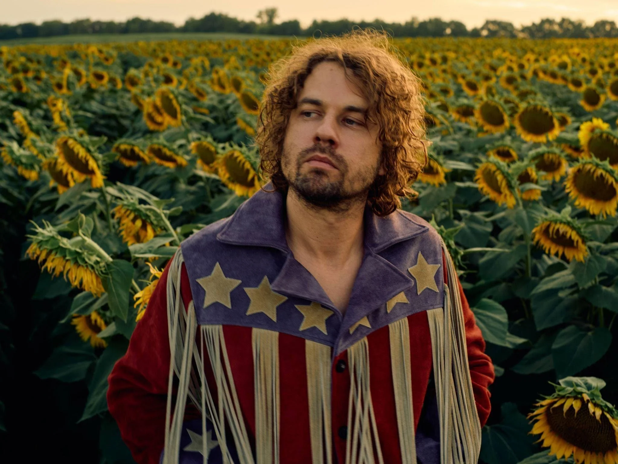 muzikant Kevin Morby staat in een veld vol zonnebloemen