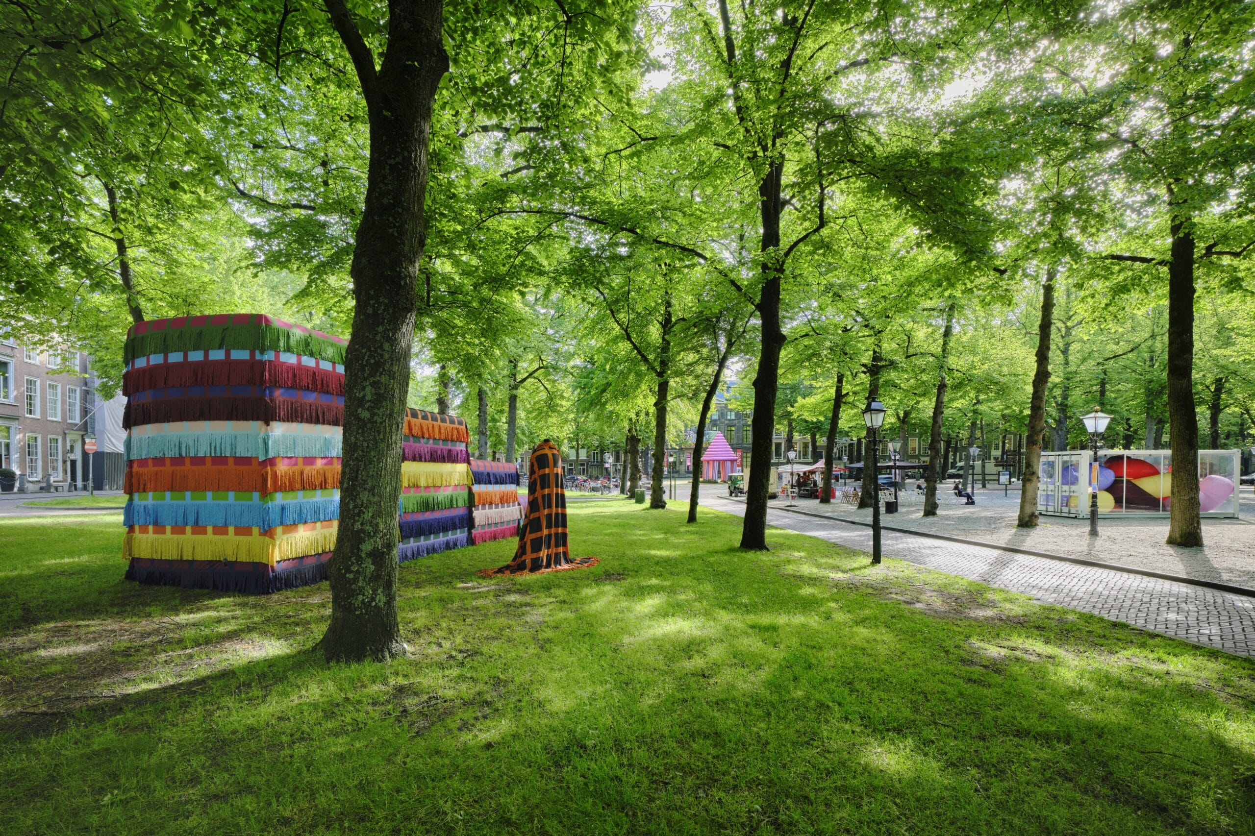 Kleurrijke kunstinstallaties met franjes en patronen tussen de groene bomen op het Lange Voorhout in Den Haag