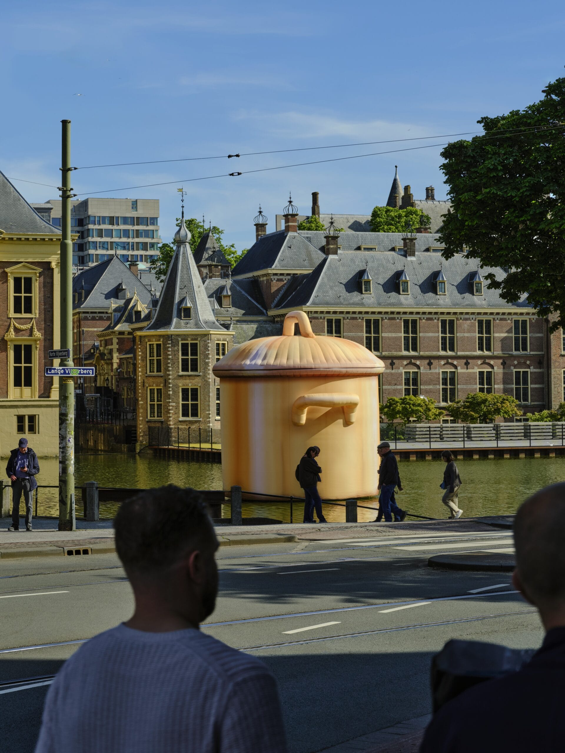 Een enorme opblaasbare oranje kookpan drijft in de Hofvijver in Den Haag, met het Binnenhof op de achtergrond