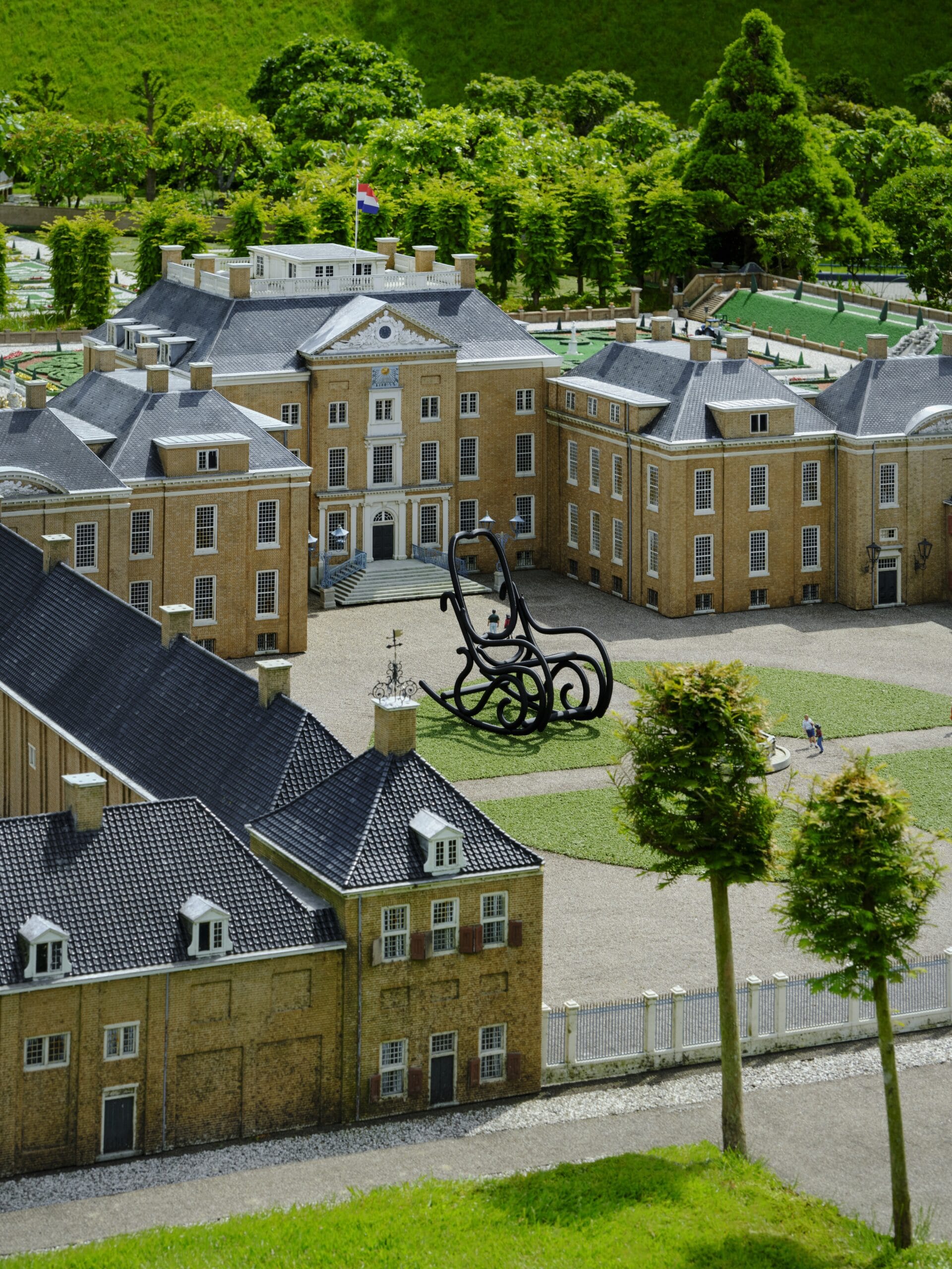 Miniatuur van Paleis Huis ten Bosch in Madurodam met een groot zwart kunstwerk van een schommelstoel op het voorplein