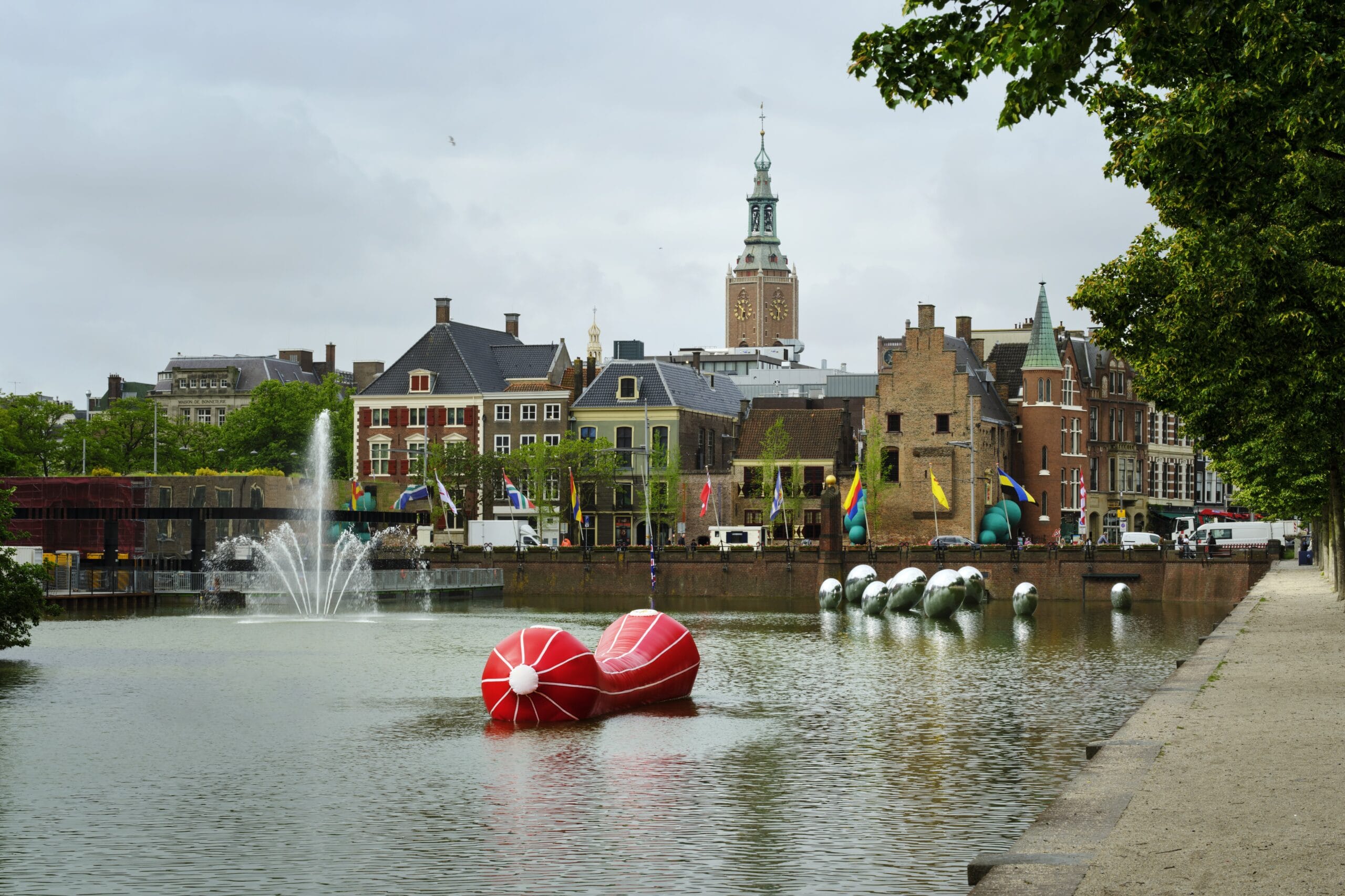 Uitzicht op de Hofvijver in Den Haag met moderne kunstobjecten in het water en de Grote Kerk op de achtergrond
