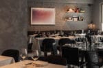 Modern en warm ingericht restaurantinterieur met houten tafels en stoelen.