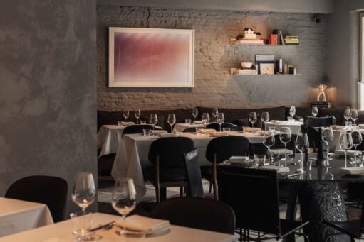 Modern en warm ingericht restaurantinterieur met houten tafels en stoelen.