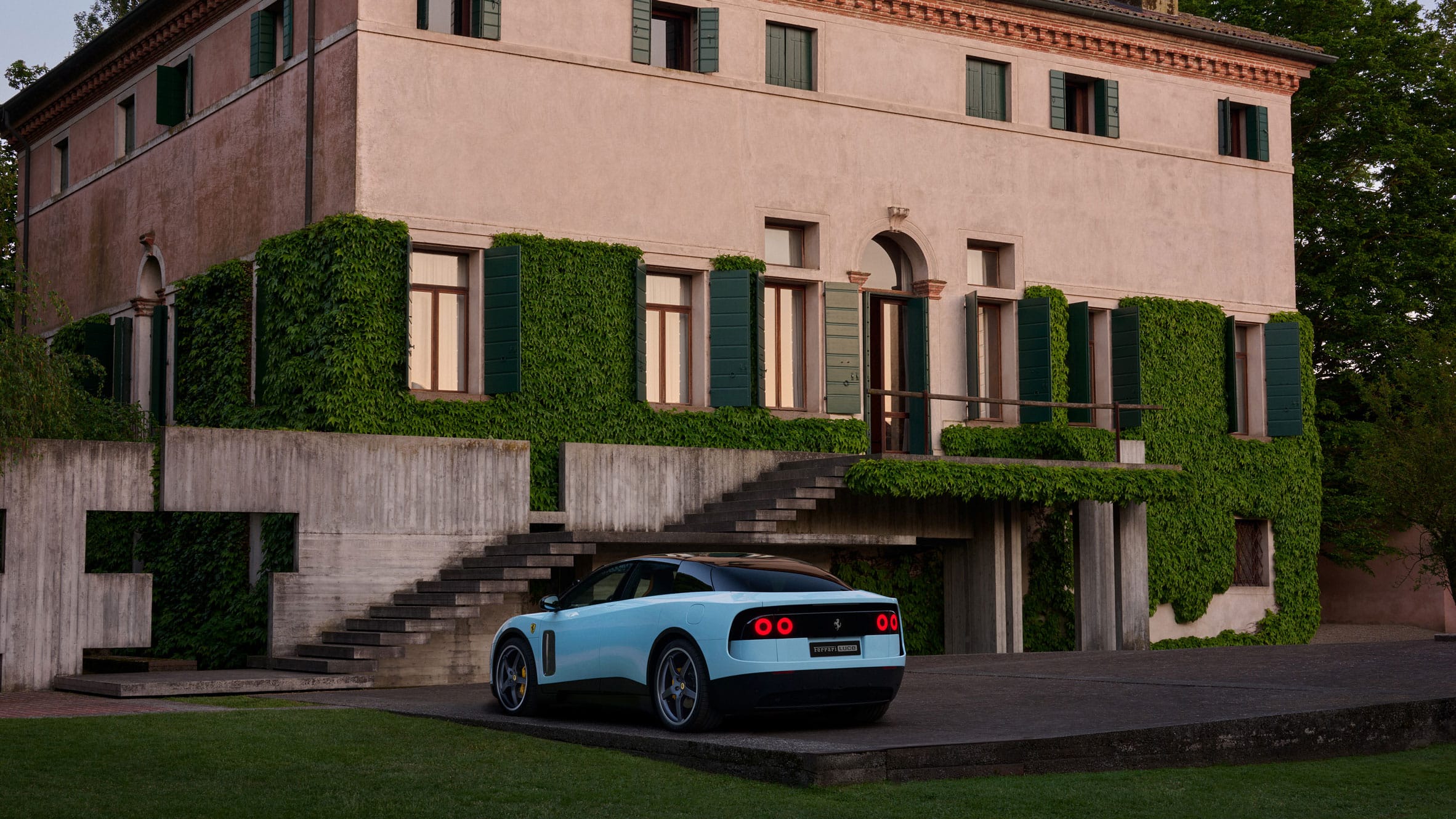 Lichtblauwe Ferrari Luce geparkeerd voor een klassieke Italiaanse villa met klimop en groene luiken