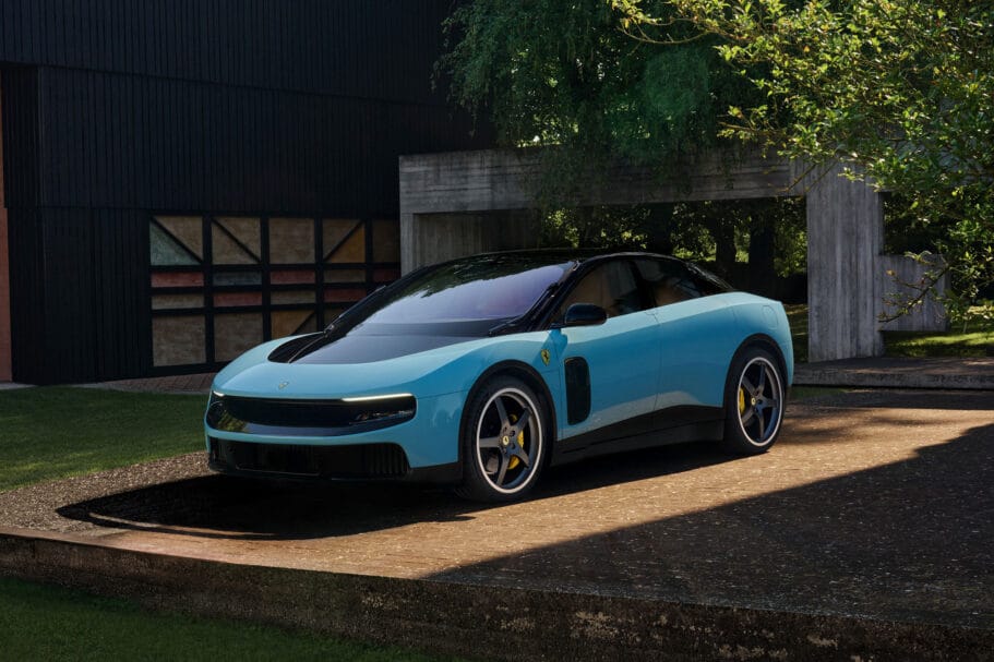 Lichtblauwe Ferrari Luce geparkeerd op een oprit voor een modern gebouw met zwarte houten gevels