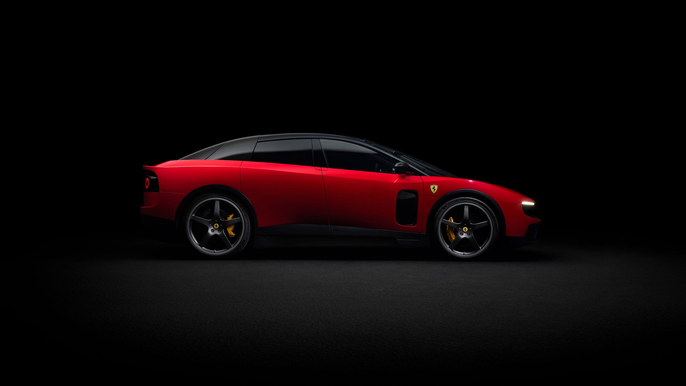 Zijaanzicht van een rode Ferrari Luce tegen een zwarte achtergrond
