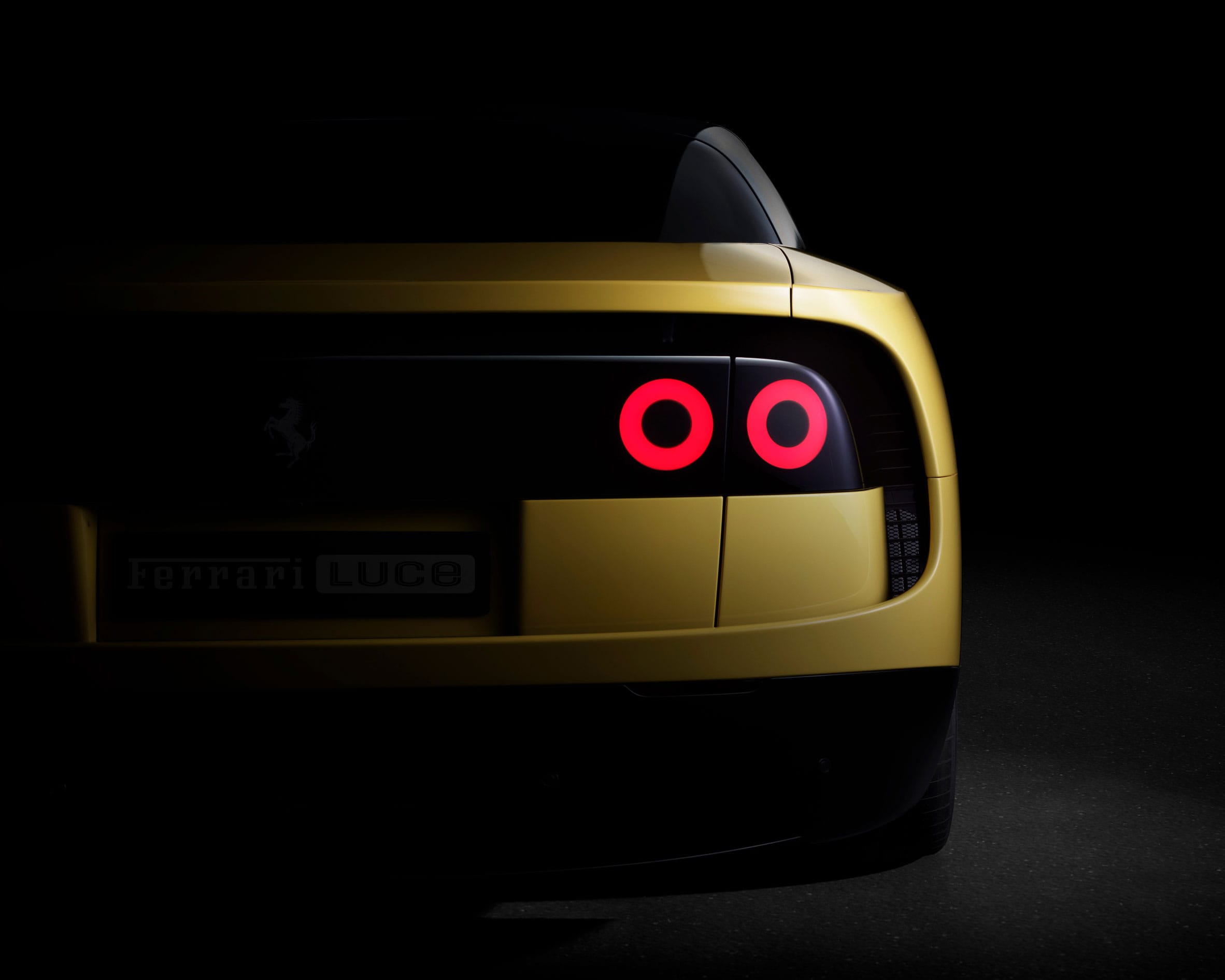 Achteraanzicht van een gele Ferrari Luce in het donker met brandende ronde achterlichten