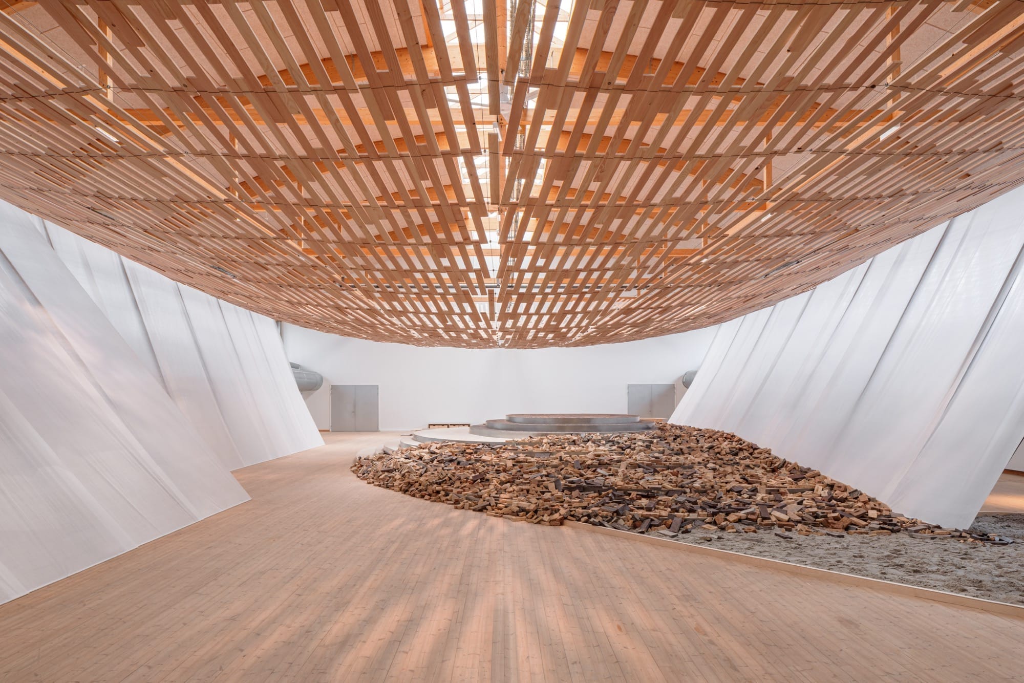 Een zwevende overkapping van houten latten in een grote tentoonstellingsruimte