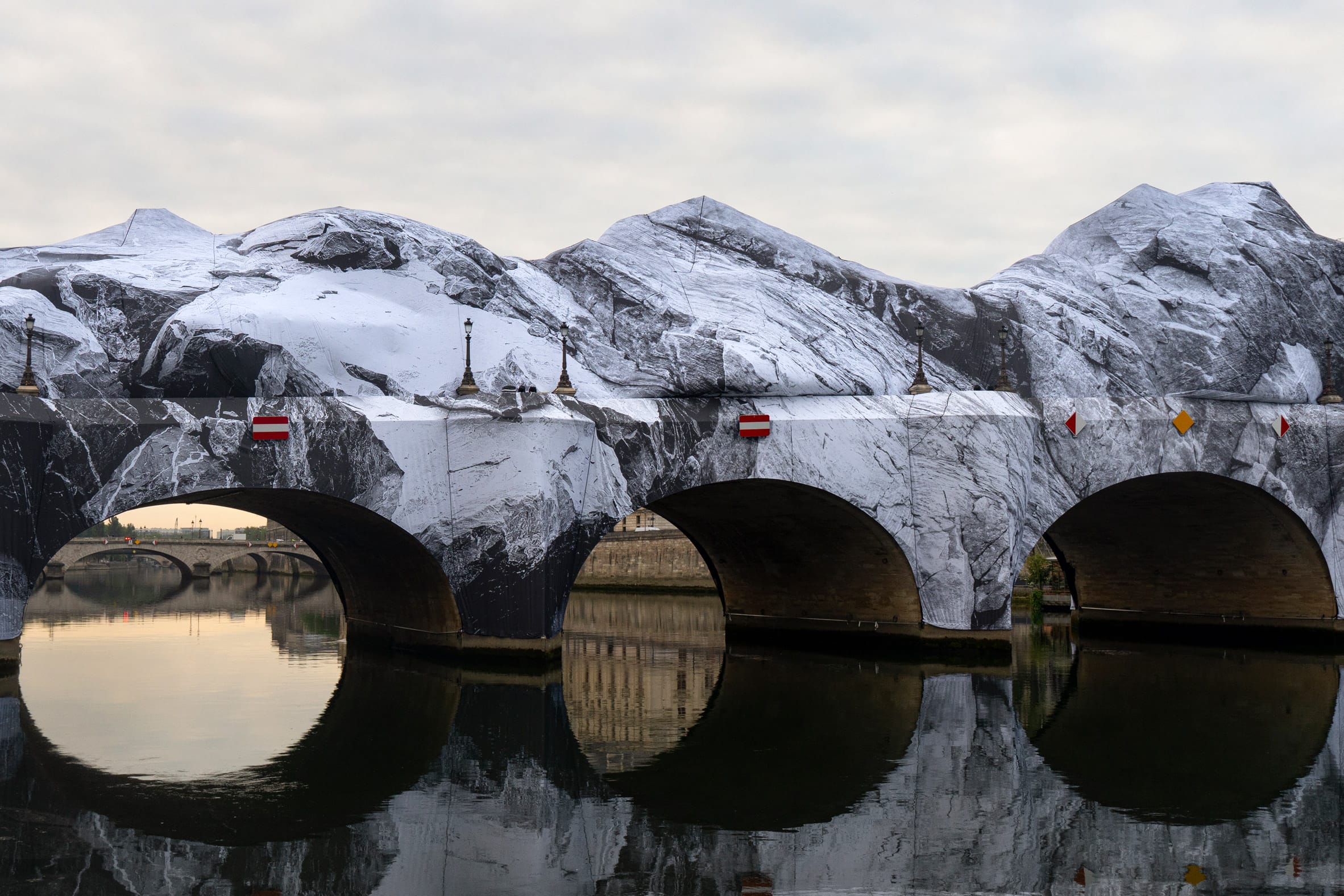De Pont Neuf in Parijs volledig ingepakt in doeken met een zwart-wit print van rotsachtige bergen