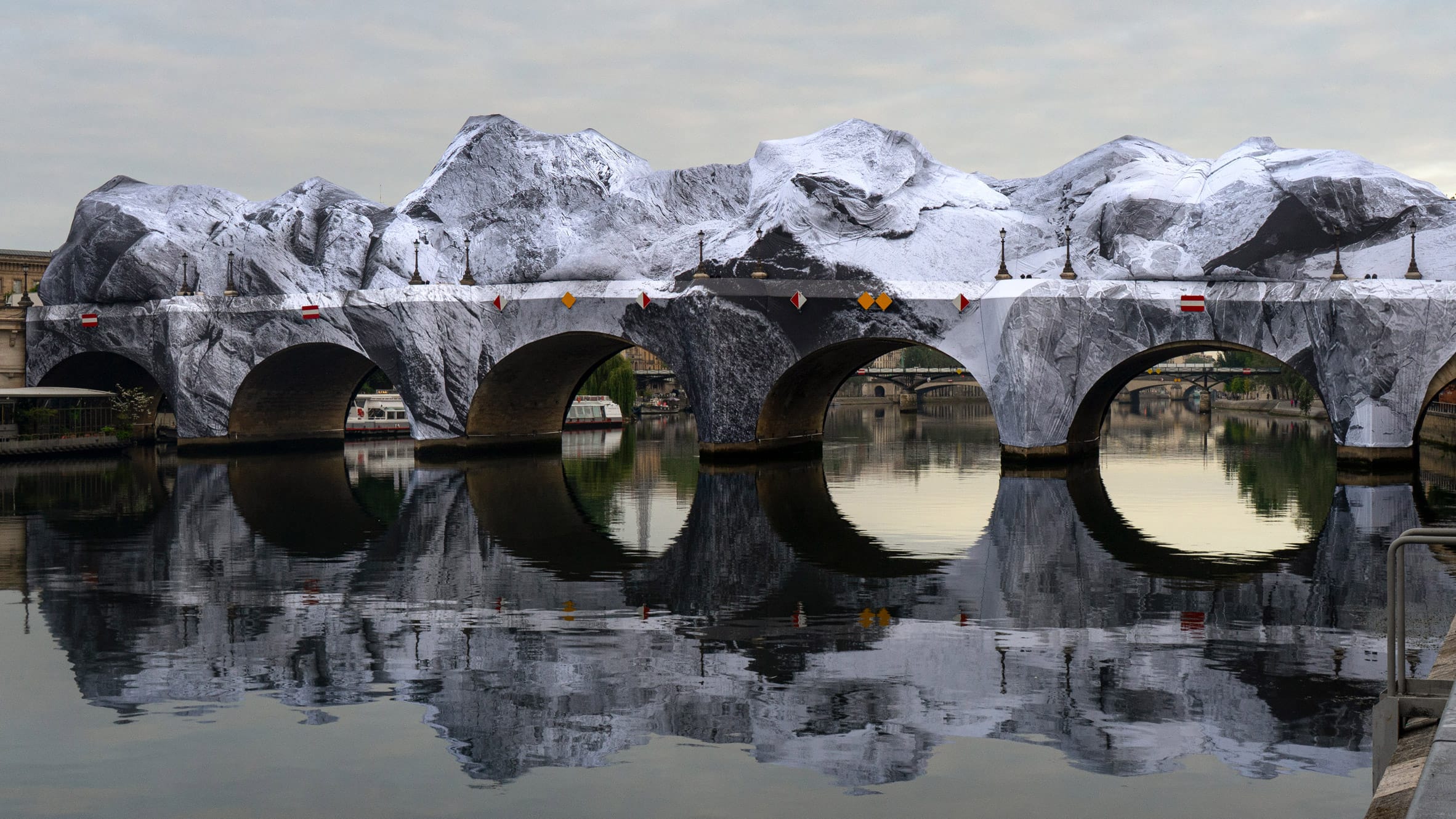 De Pont Neuf in Parijs volledig ingepakt in doeken met een print van besneeuwde bergtoppen