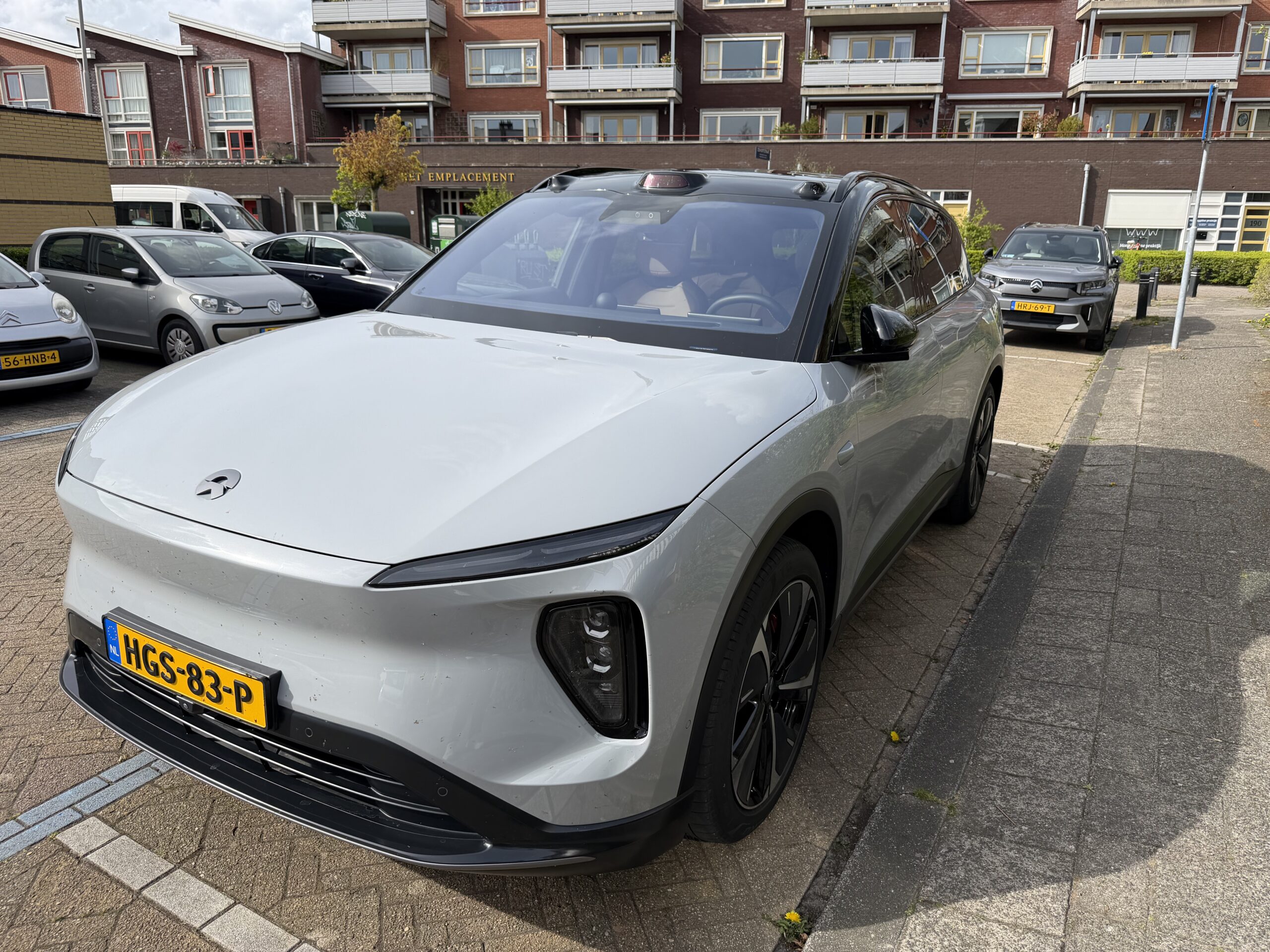 Grijze NIO EL7 geparkeerd op een parkeerplaats voor een appartementencomplex