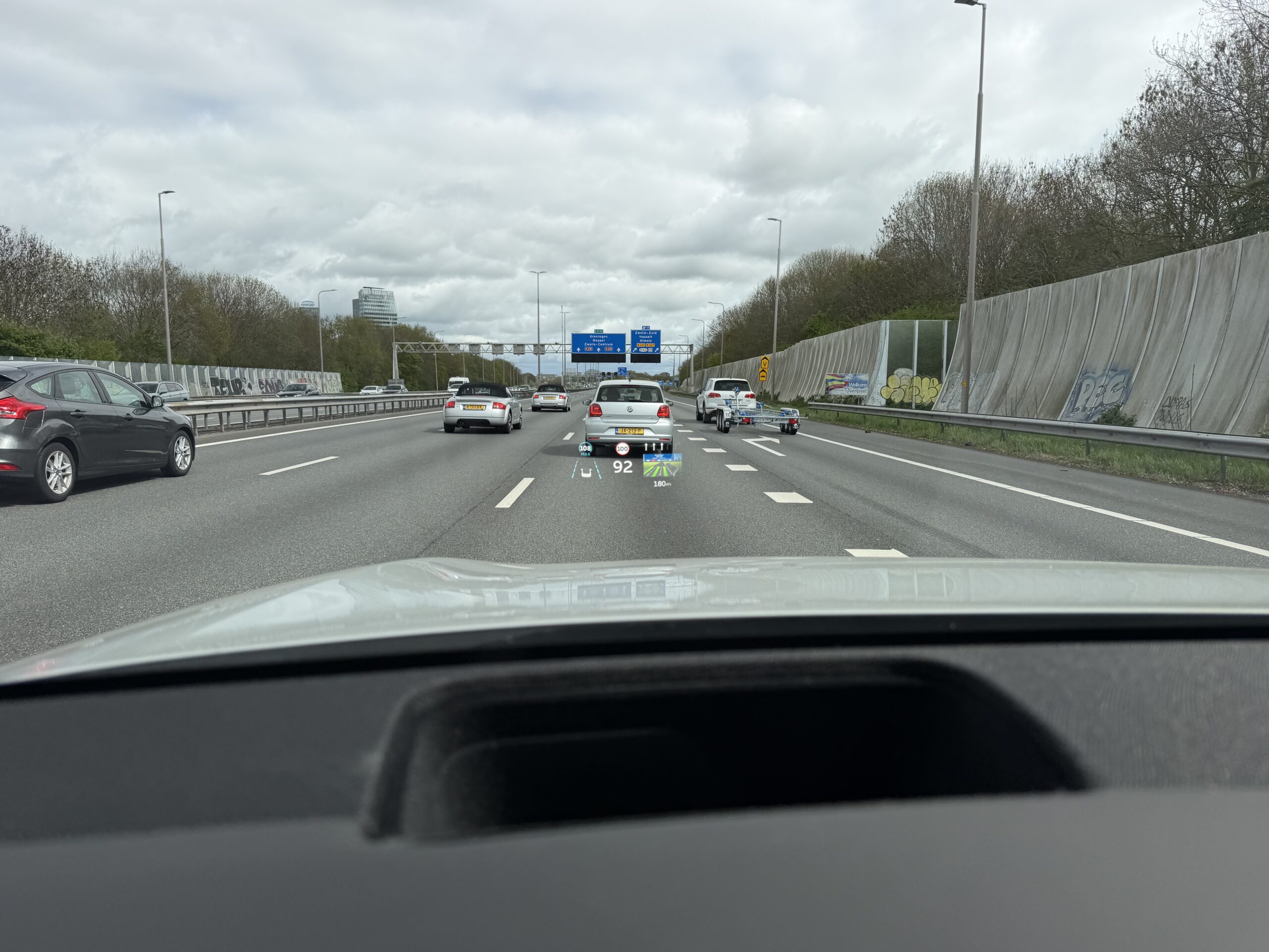 Zicht vanuit een auto op een snelweg met een head-up display dat de snelheid en navigatie op de voorruit projecteert