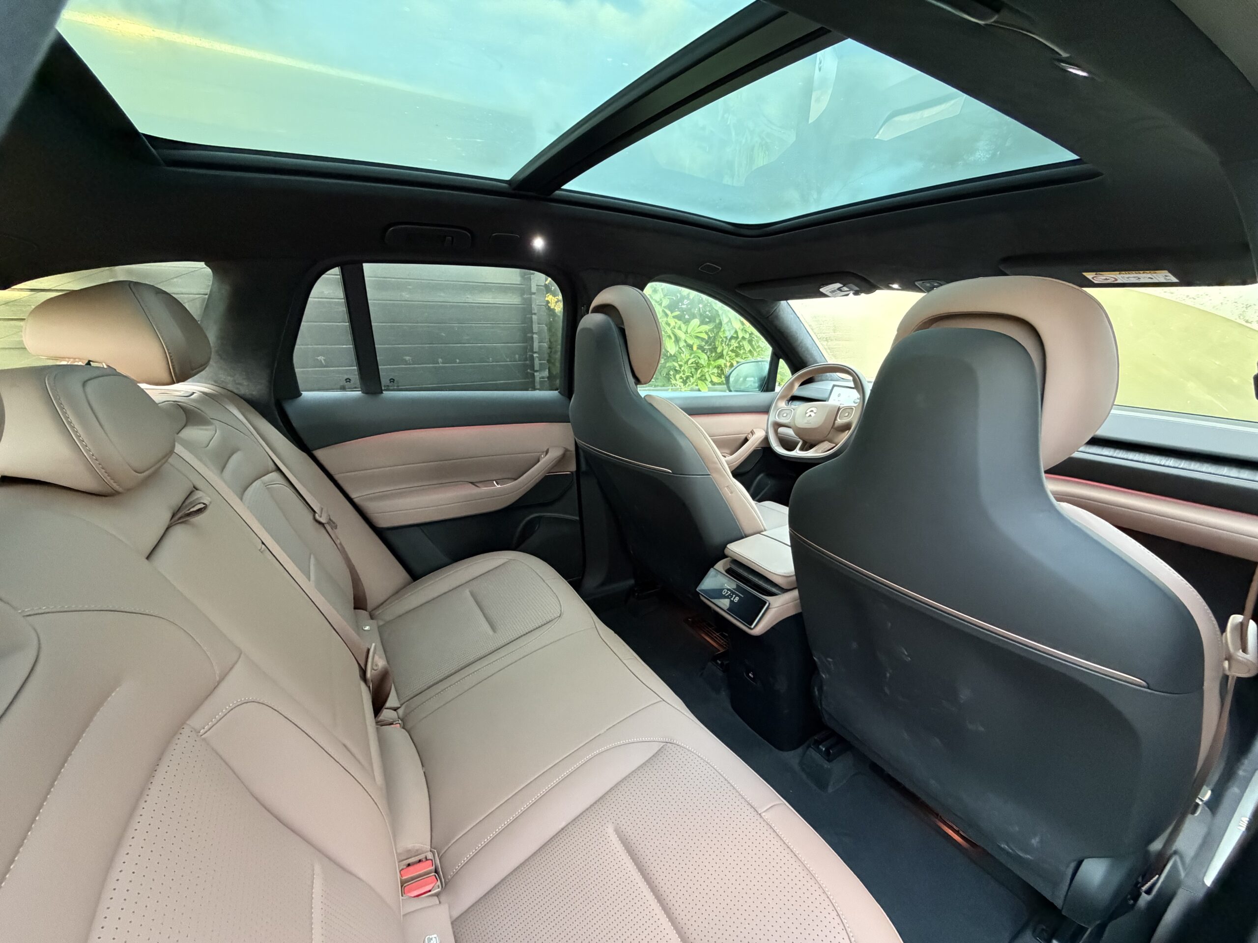 Interieur van een moderne auto met beige lederen bekleding, een panoramisch glazen dak en sfeerverlichting