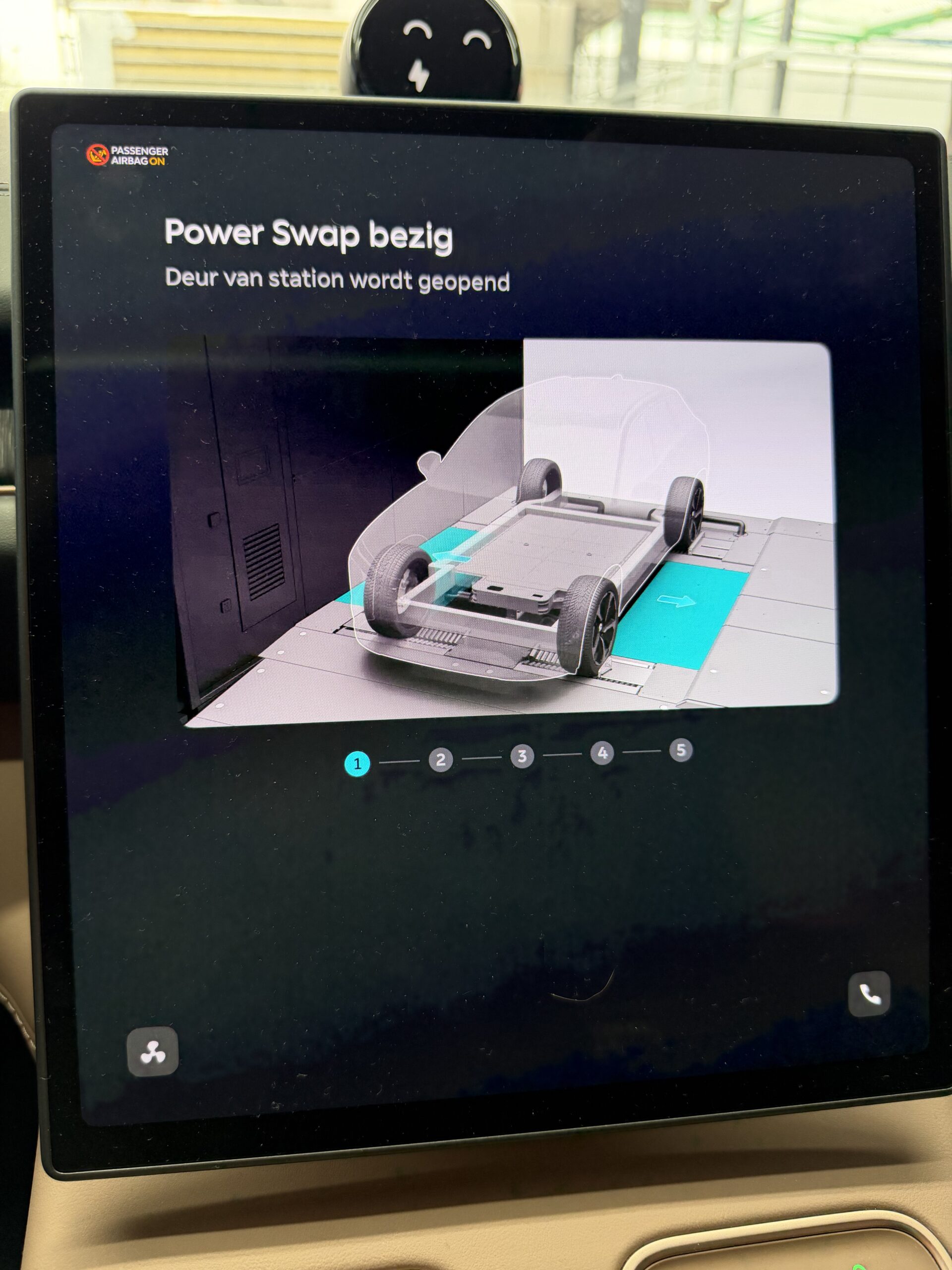 Scherm in een auto toont Power Swap bezig, stap 1 van 5: Deur van station wordt geopend met een illustratie van de auto