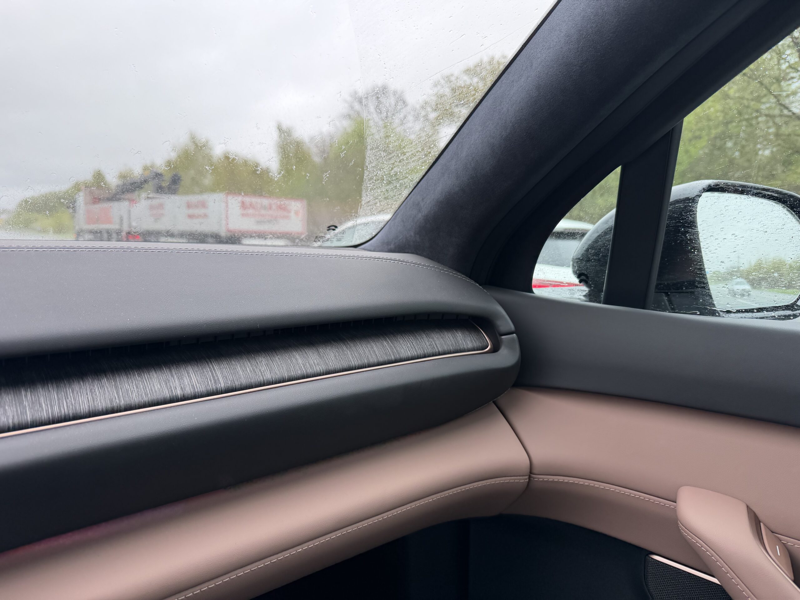 Interieur van een auto met een tweekleurig dashboard in zwart en beige, voorzien van een houten sierstrip