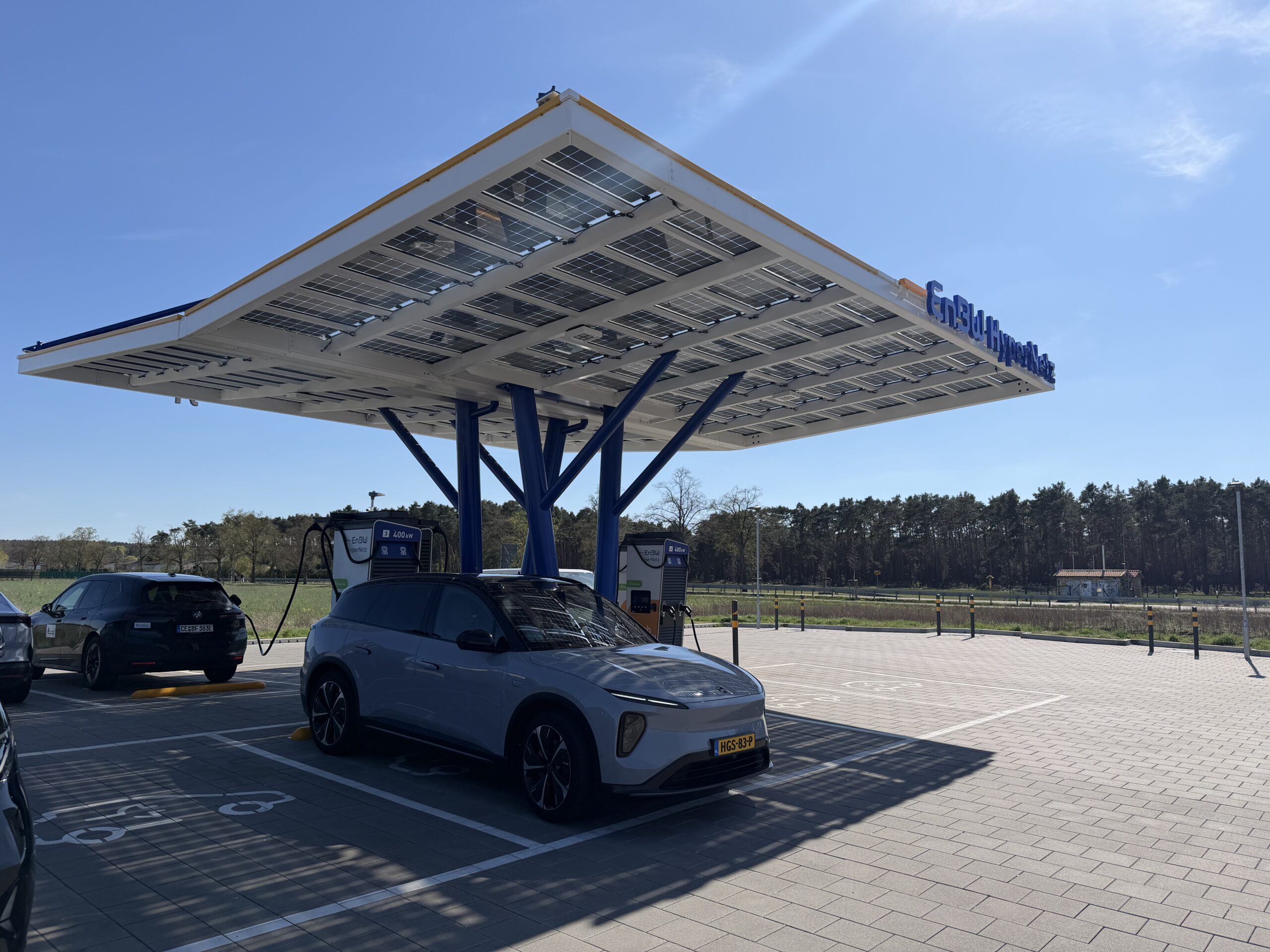 Een elektrische auto laadt op bij een EnBW HyperNetz-station onder een overkapping van zonnepanelen