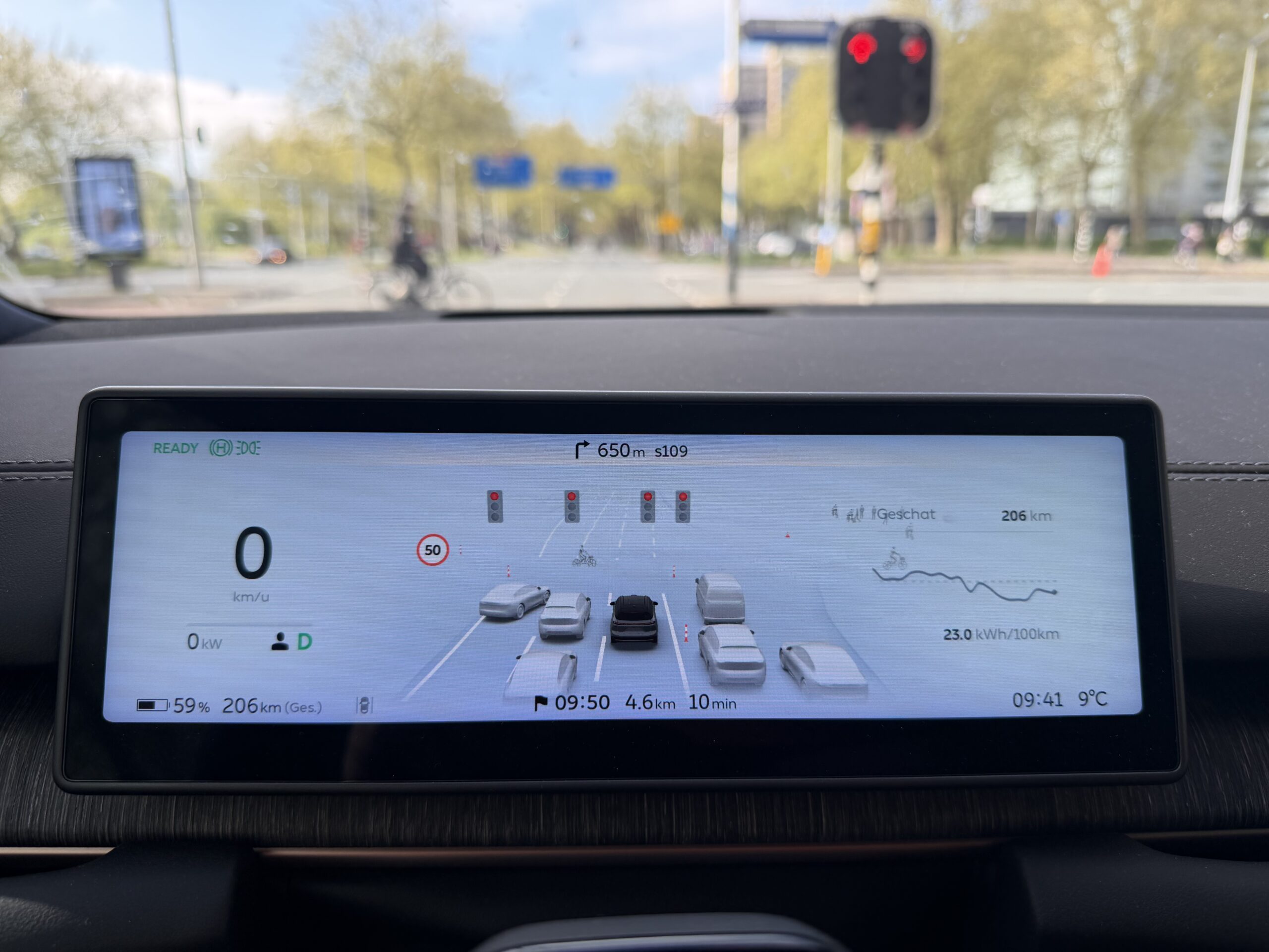 Digitaal dashboard van een auto toont een visualisatie van omringend verkeer, rode verkeerslichten en navigatie-info