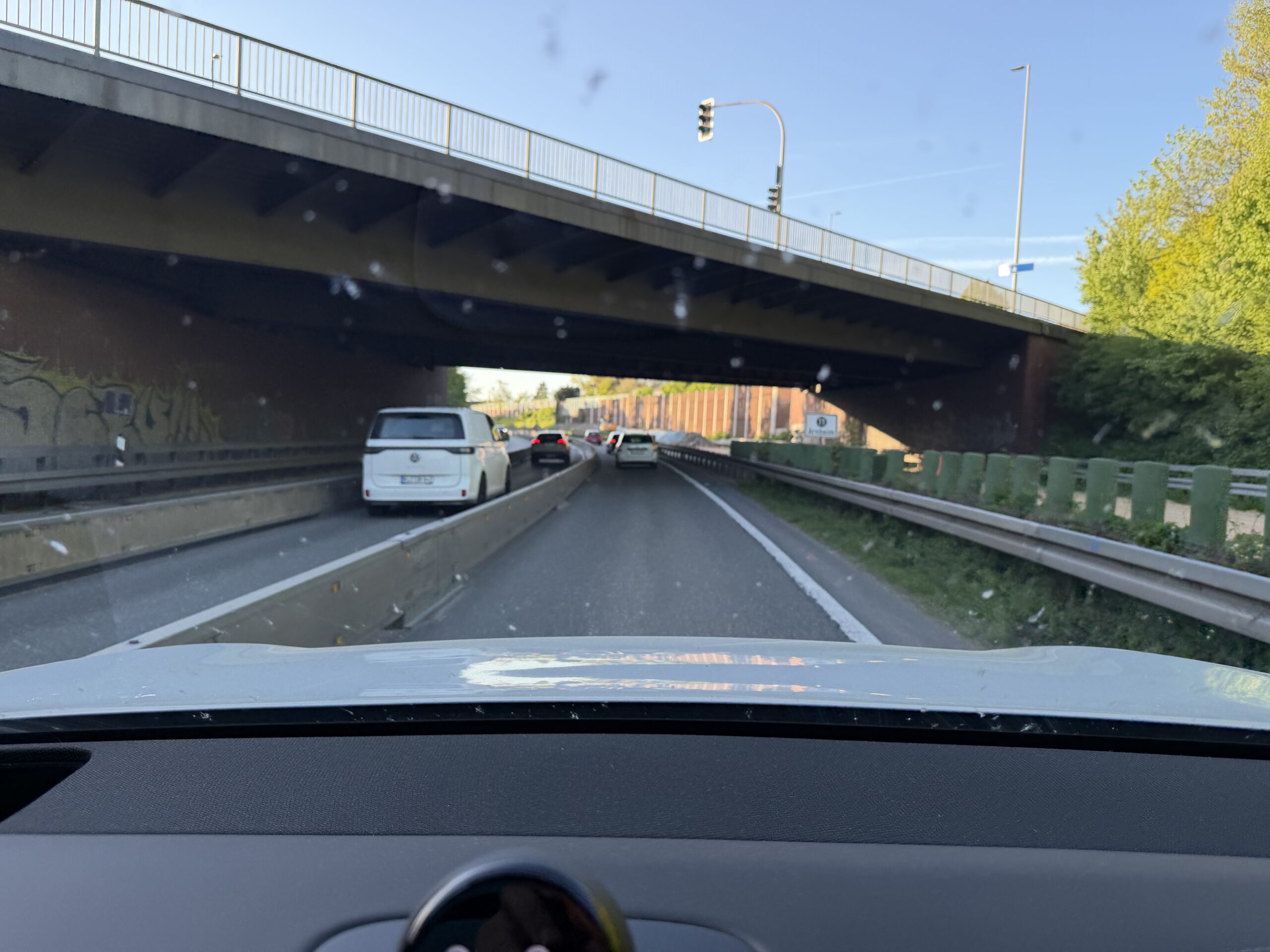 Zicht vanuit een auto op een snelweg die onder een viaduct doorloopt, met verkeer voor de auto
