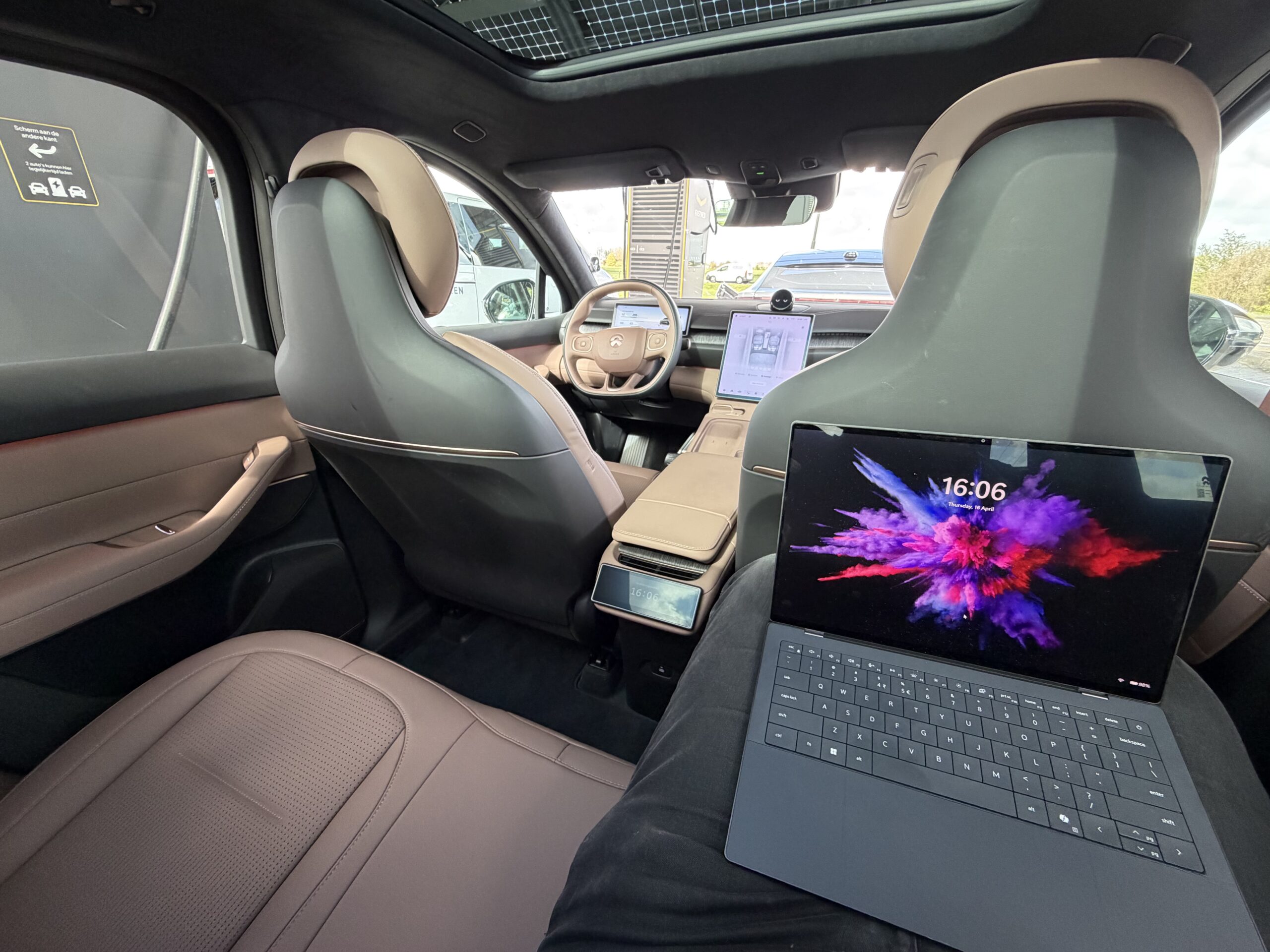 Interieur van een moderne auto met een laptop op schoot van een passagier op de achterbank