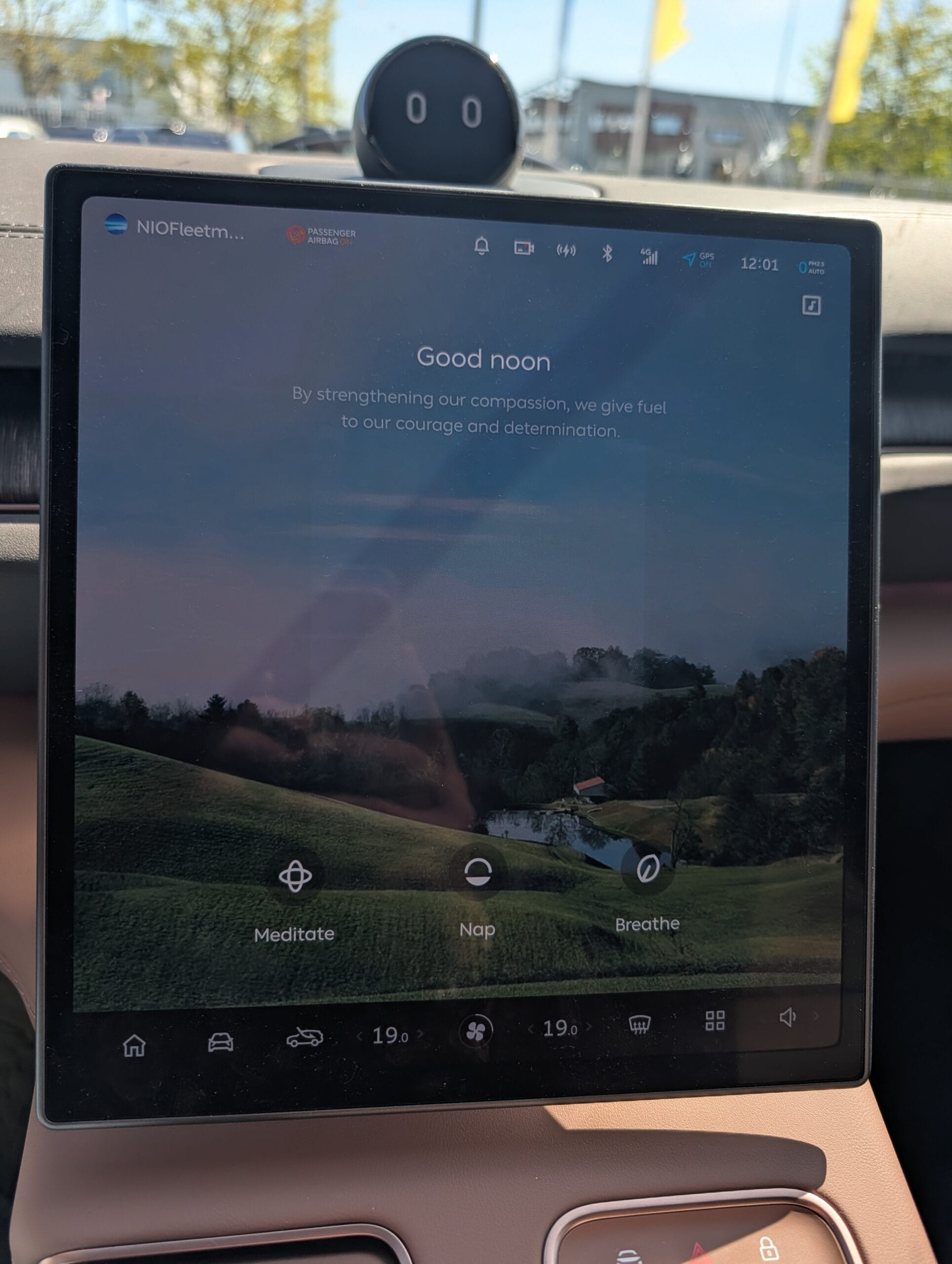 Infotainmentscherm in een NIO-auto met opties voor Mediteren, Slapen en Ademhalen tegen een achtergrond van een landschap