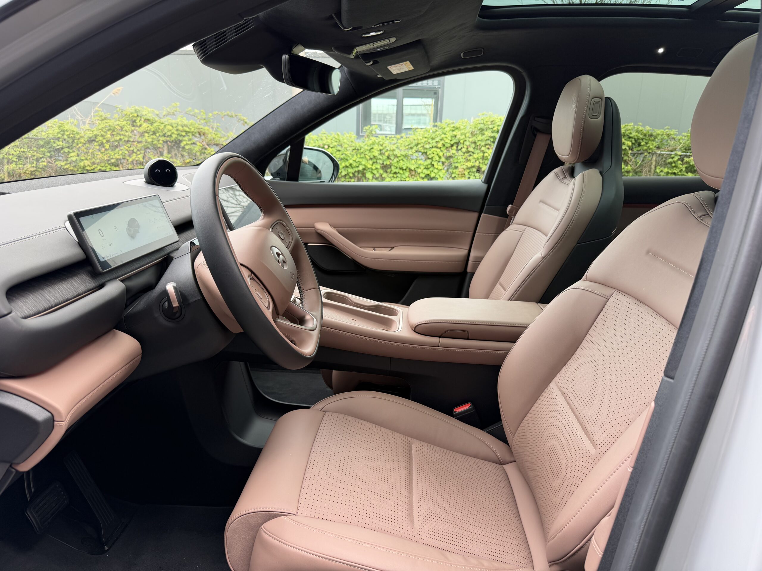 Modern auto-interieur met roze lederen bekleding, een digitaal dashboard en een minimalistisch stuurwiel