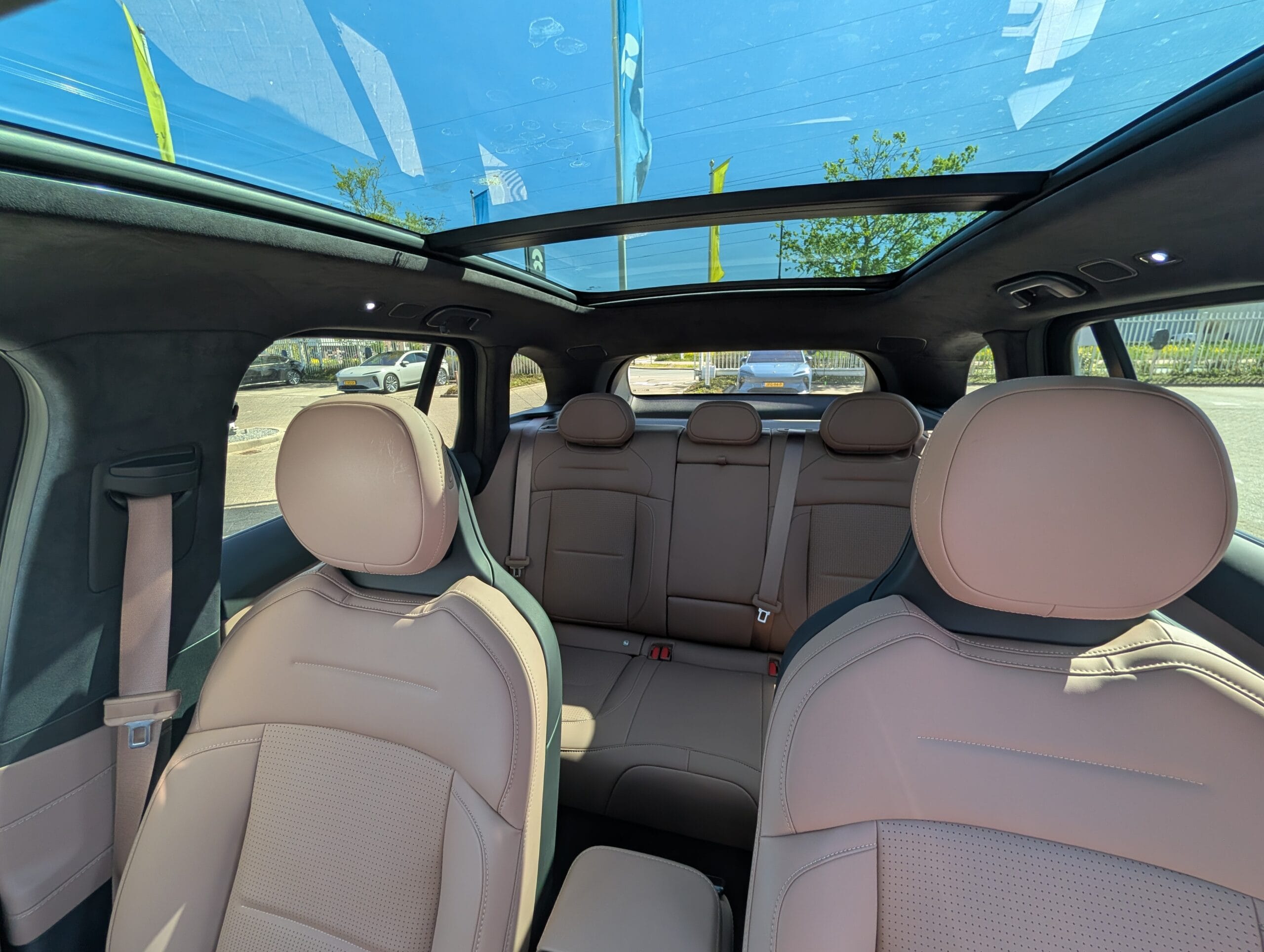 Interieur van een auto met beige lederen bekleding en een groot panoramisch glazen dak