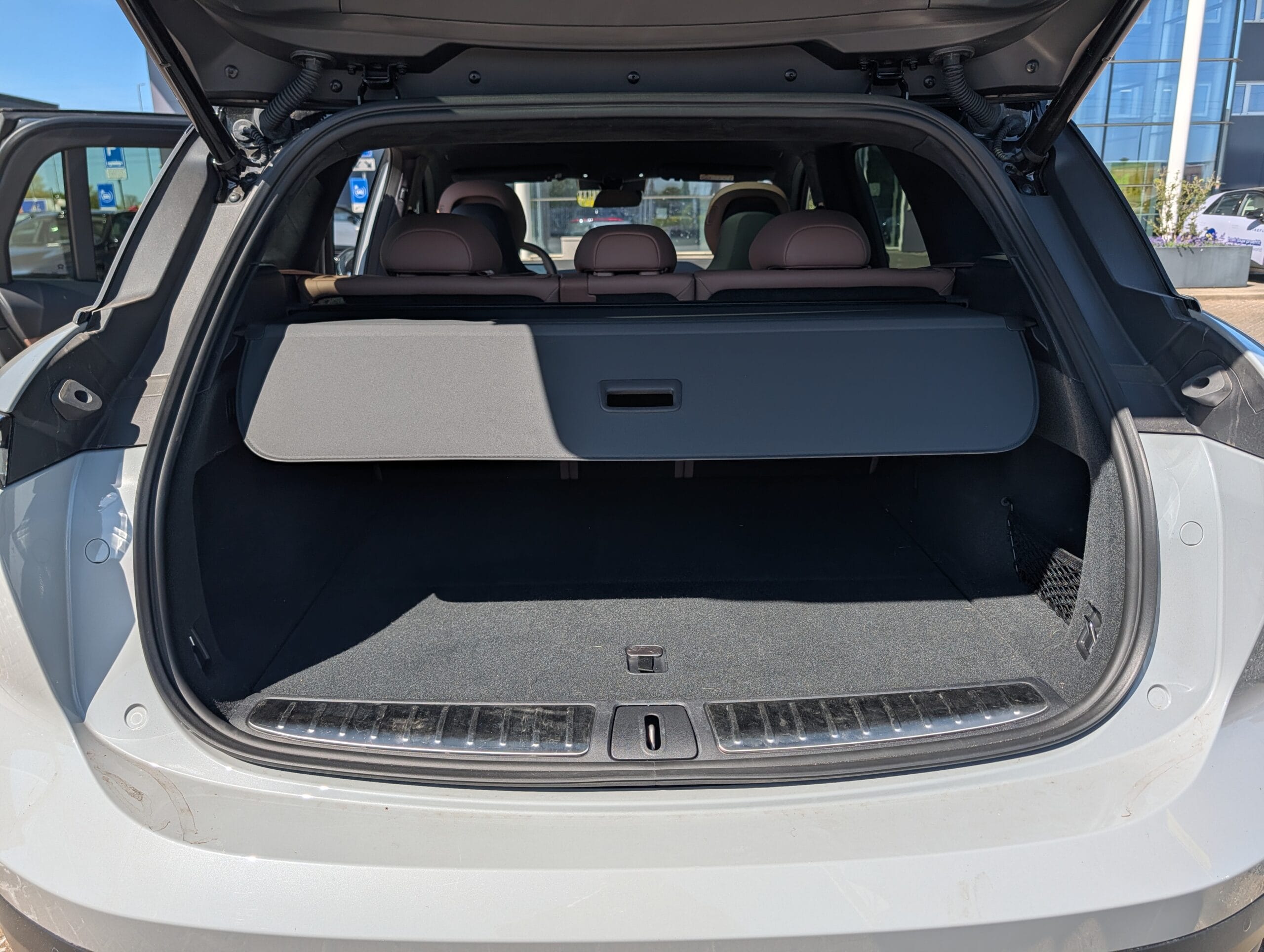 De lege kofferbak van een auto met een uitgetrokken bagageafdekking en zicht op de achterbank