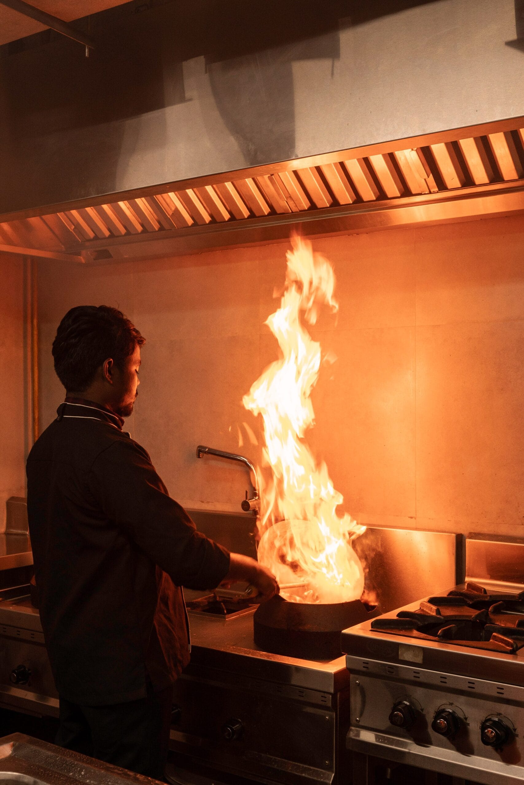 man in de keuken is iets aan het flambere