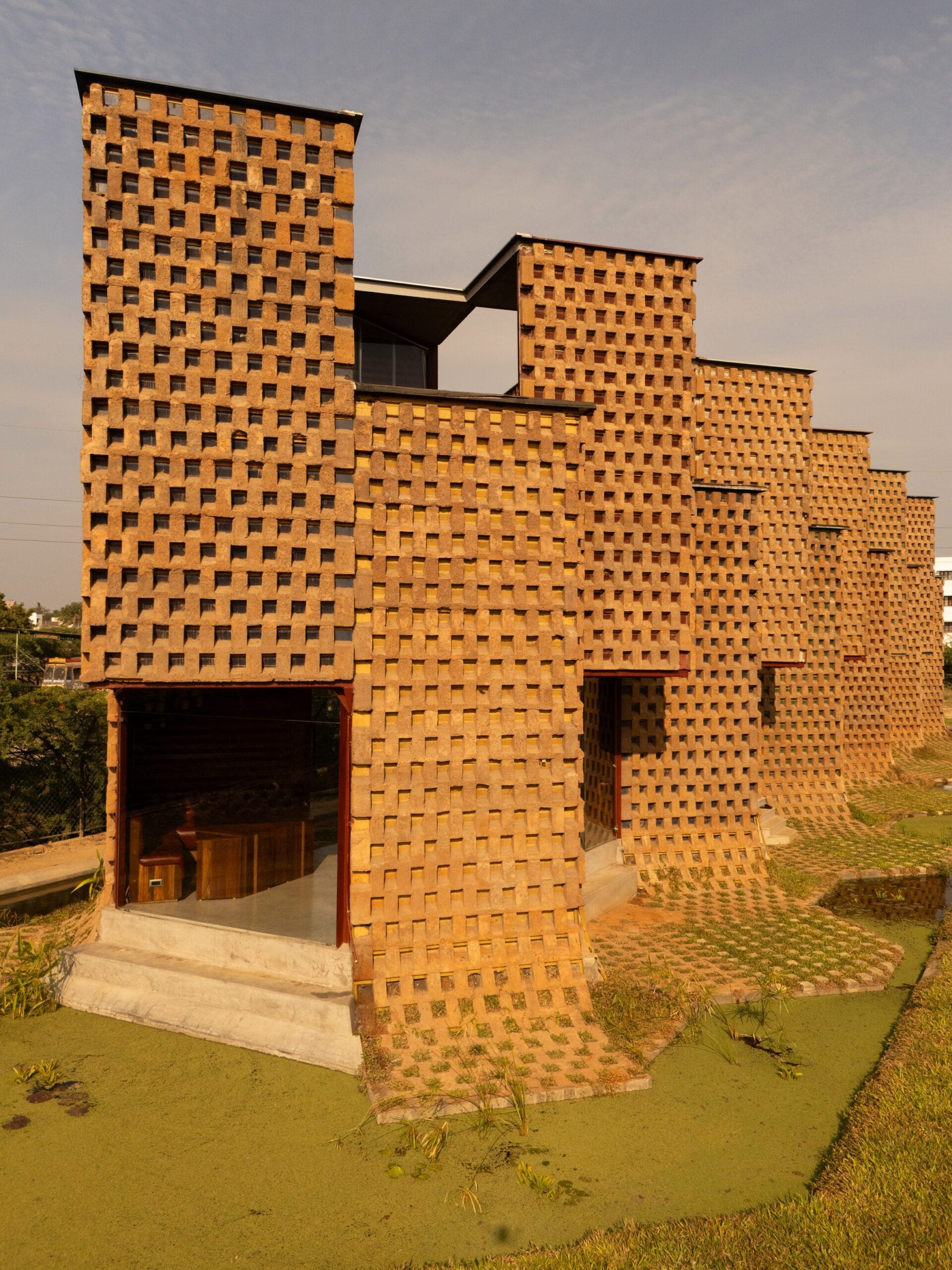 Vooraanzicht van een modern restaurant in India met een gevel van verticale zeecontainers en gestorte aarde.