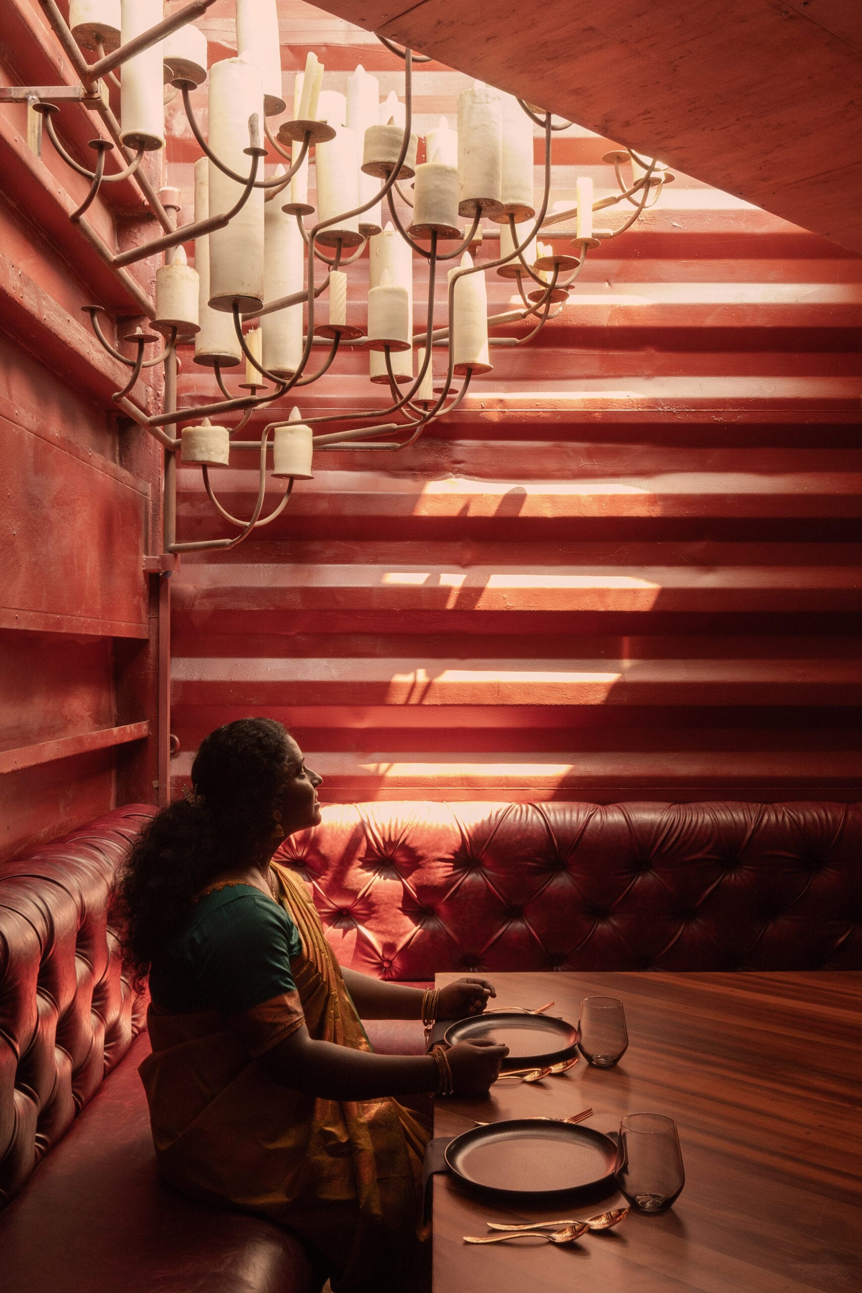 Interieur van het restaurant met dieprood geschilderde wanden van containerstaal en houten meubels.